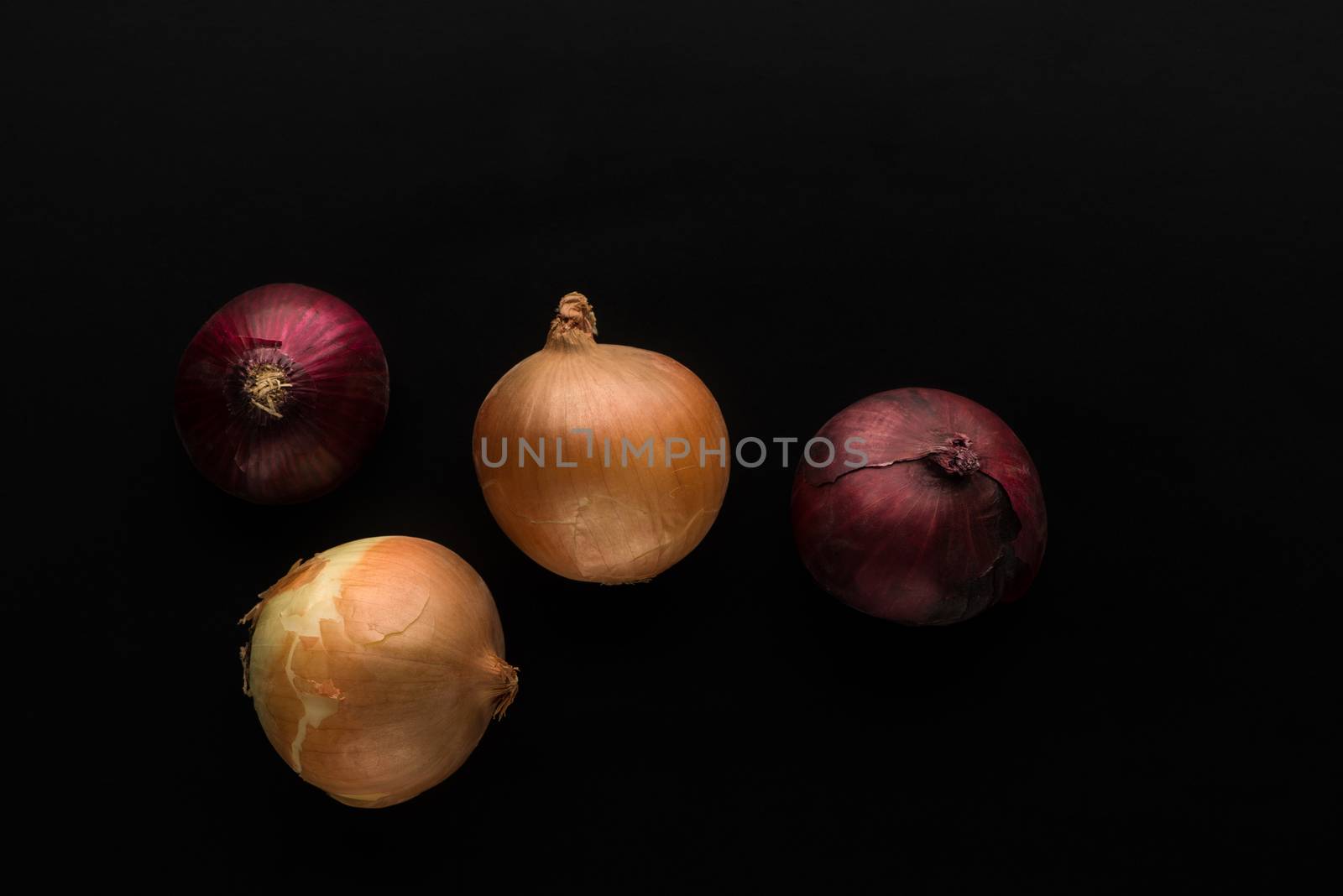 four onions of red and gold colours on a black background top view