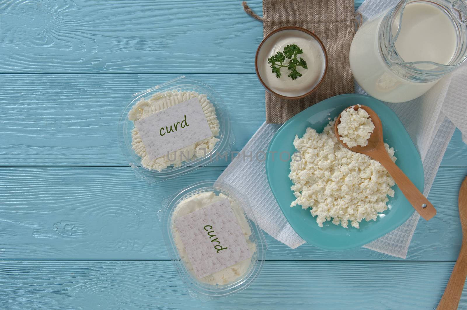 Cottage cheese in plastic packaging and milk on a wooden blue background, top view. healthy eating concept