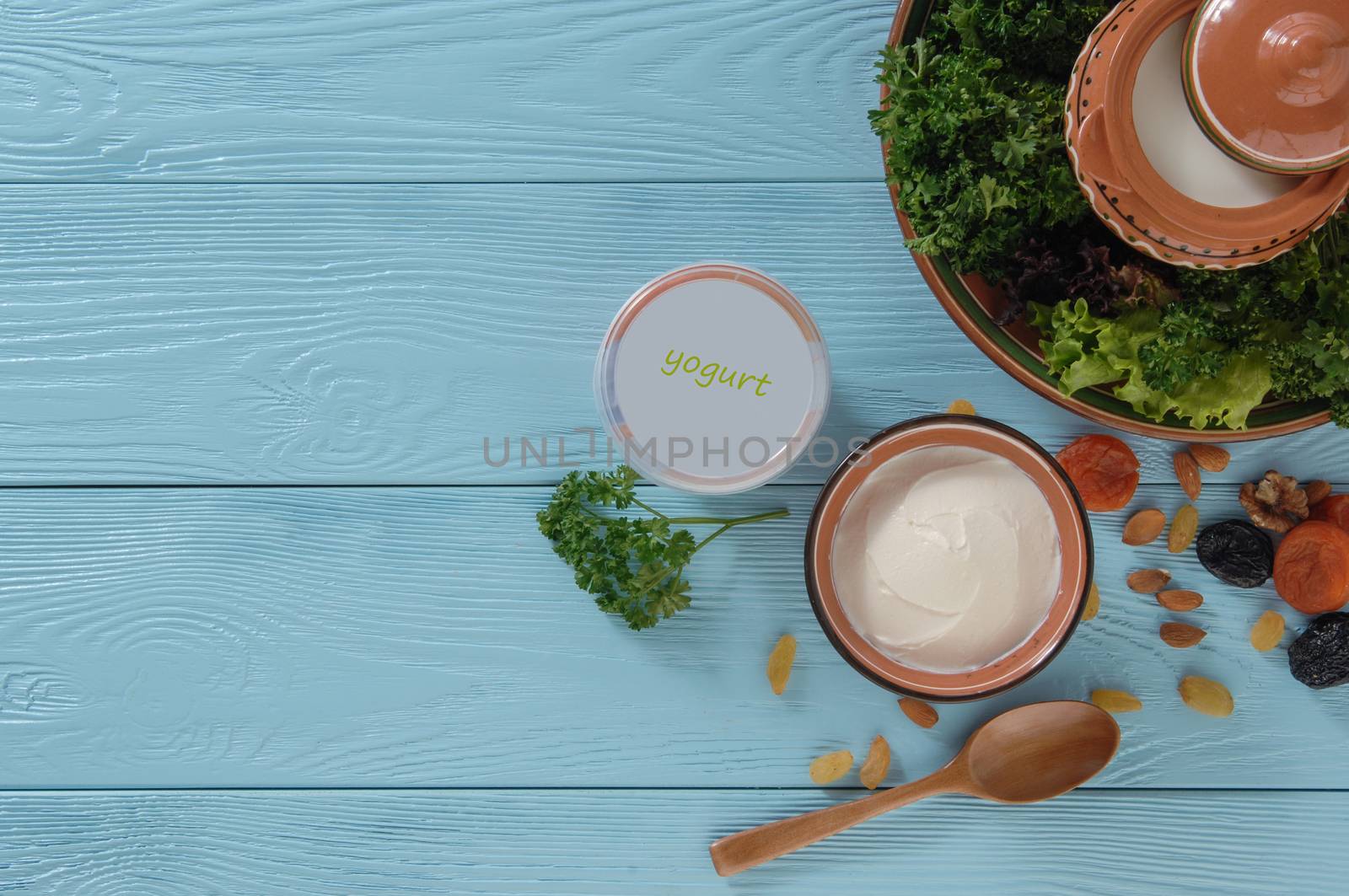 yogurt in plastic package with green salad on blue wooden background, top view. healthy eating concept