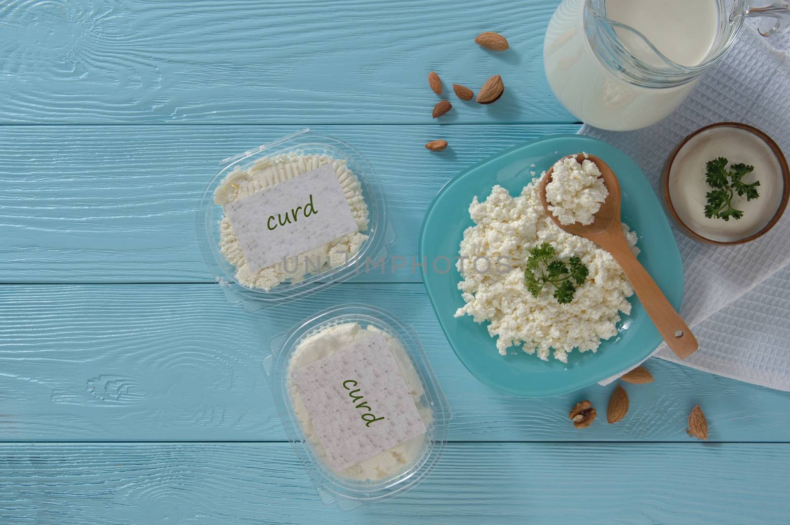 Cottage cheese in plastic packaging and milk on a wooden blue background, top view. healthy eating concept