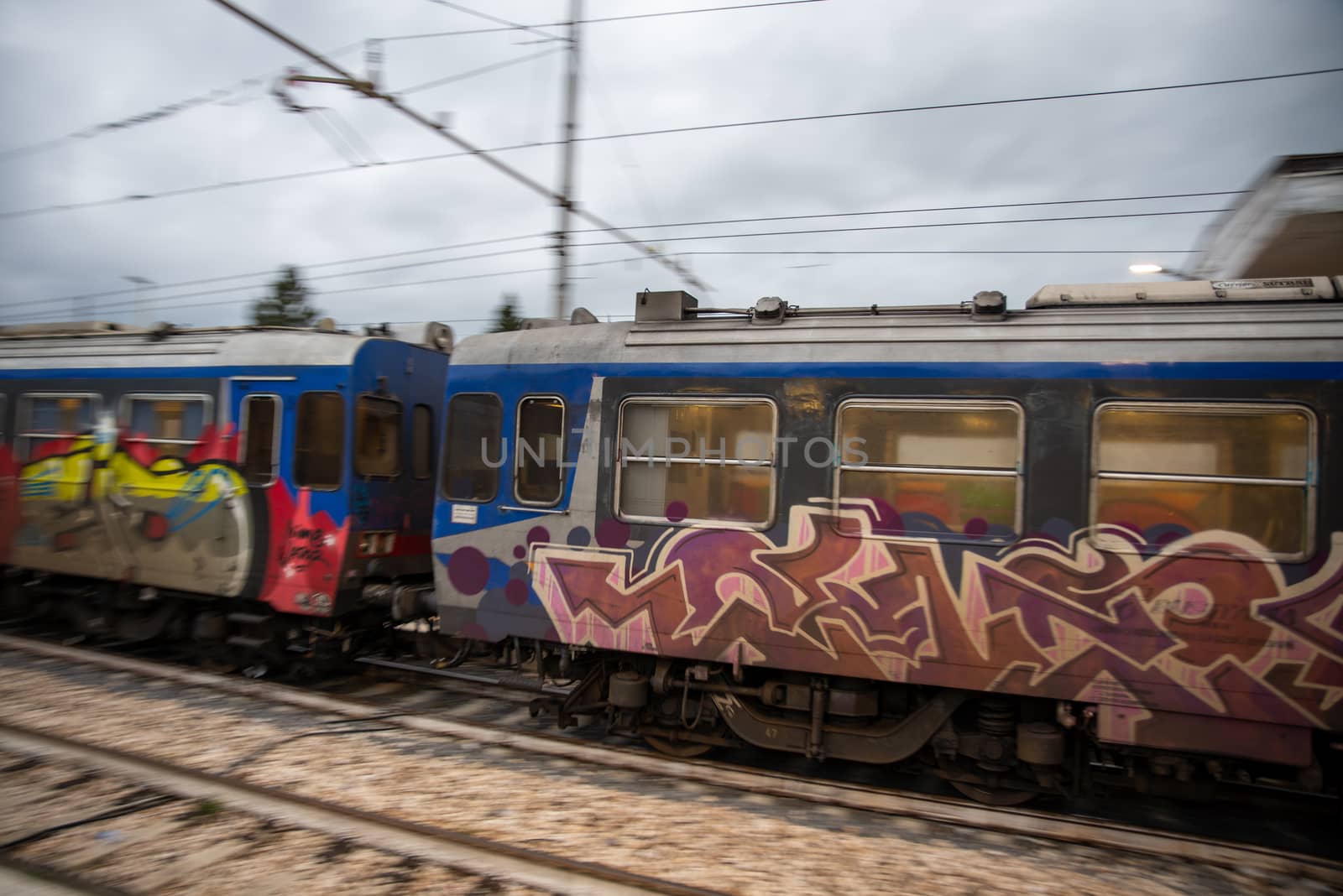 teni,italy may 28 2020 :trains panning at the station at speed with people inside and colored by graffiti
