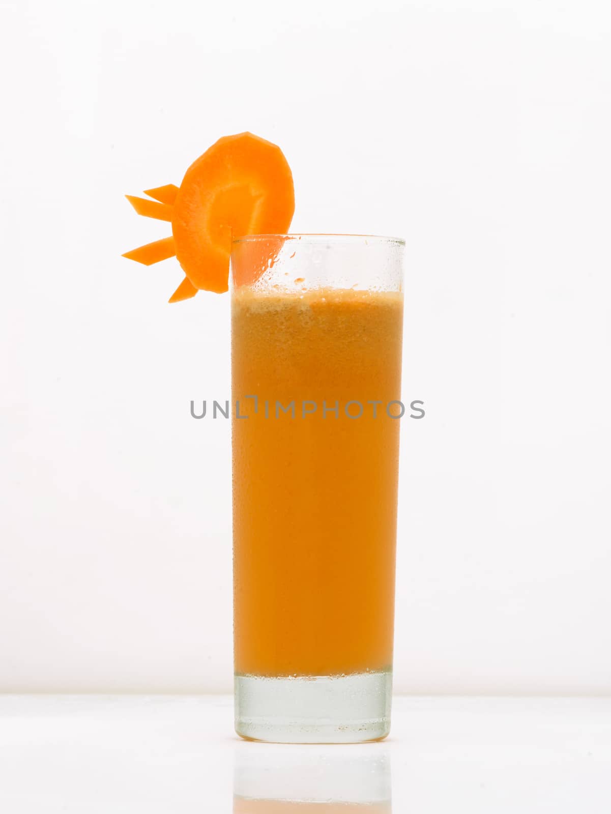 carrot drink in a glass with ice and a slice of carrot. drink isolated on white background