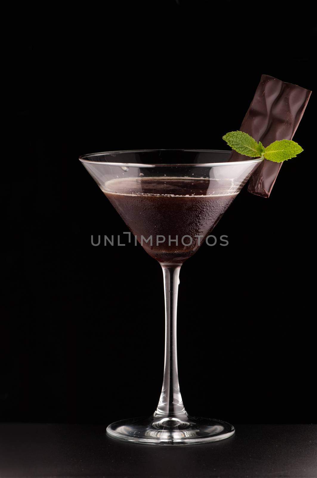 one glass cup with a drink and chocolate on a dark background