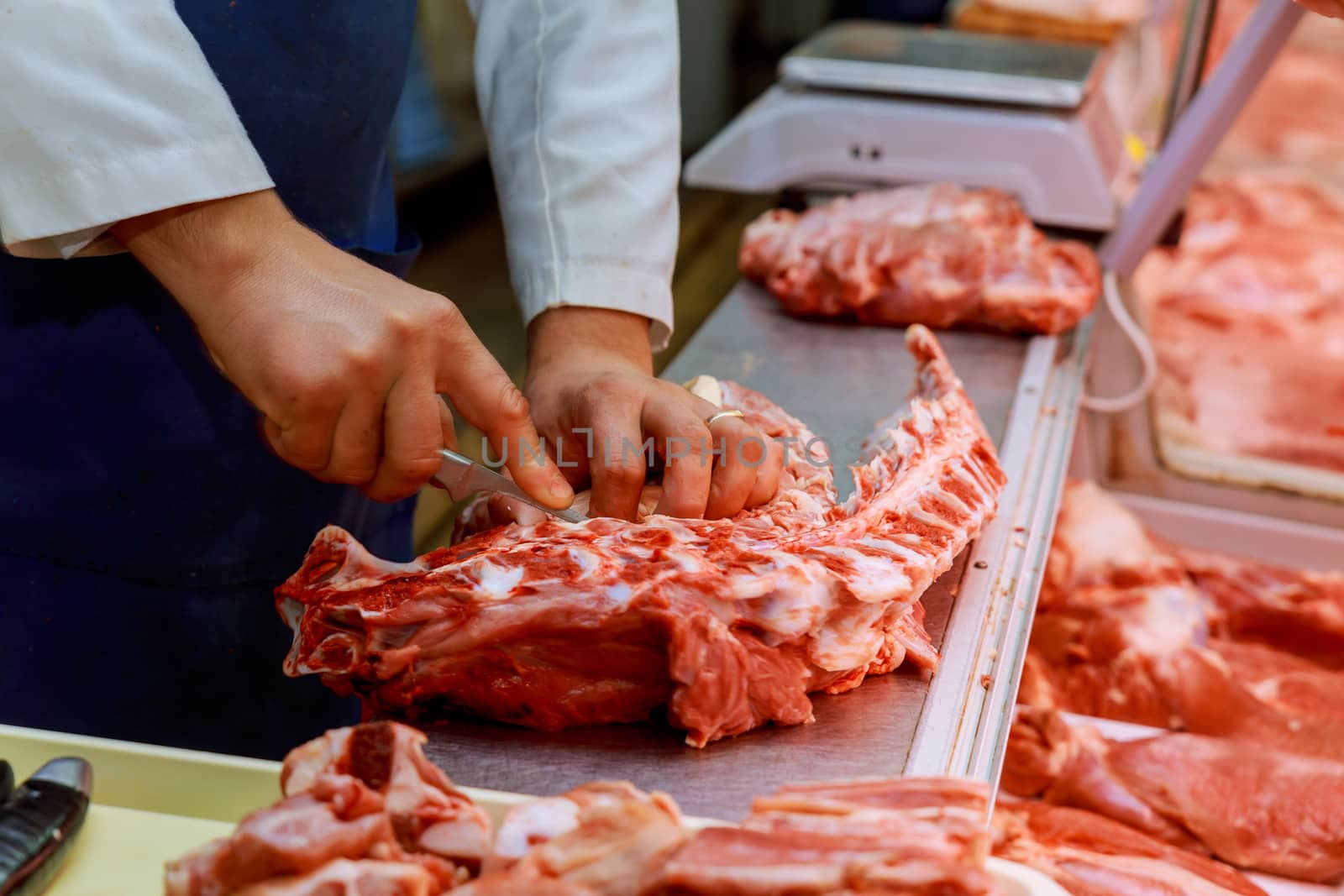 Hands of a butcher cutting slices of raw meat by ungvar