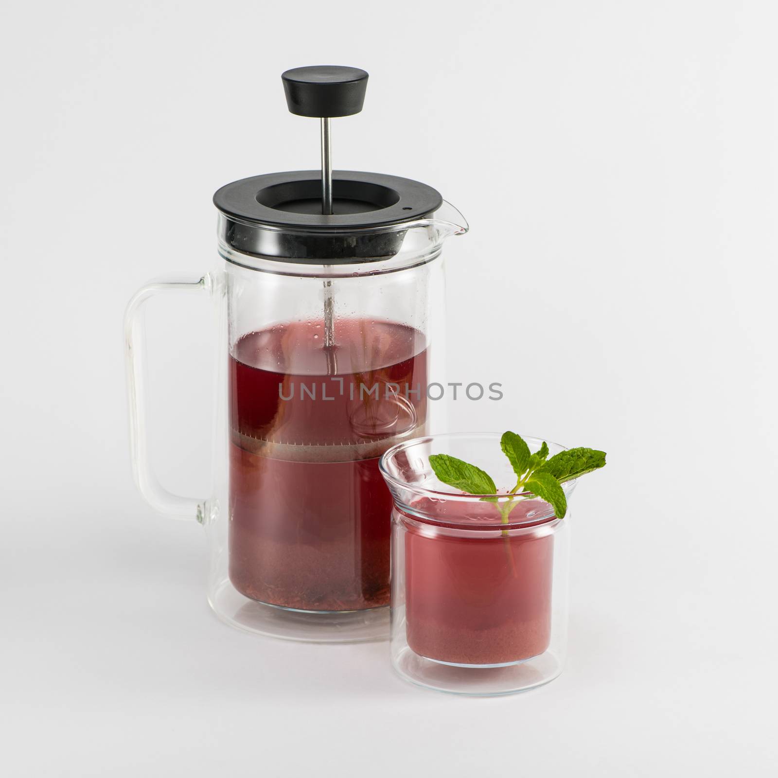 transparent teapot with fruit drink and glass with mint on white background, isolated. piston teapot