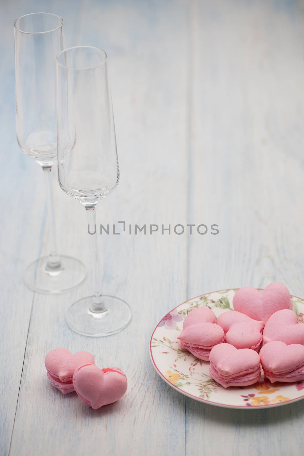 pink cookies in the shape of hearts on a plate and champagne glasses on wooden boards on Valentine's Day