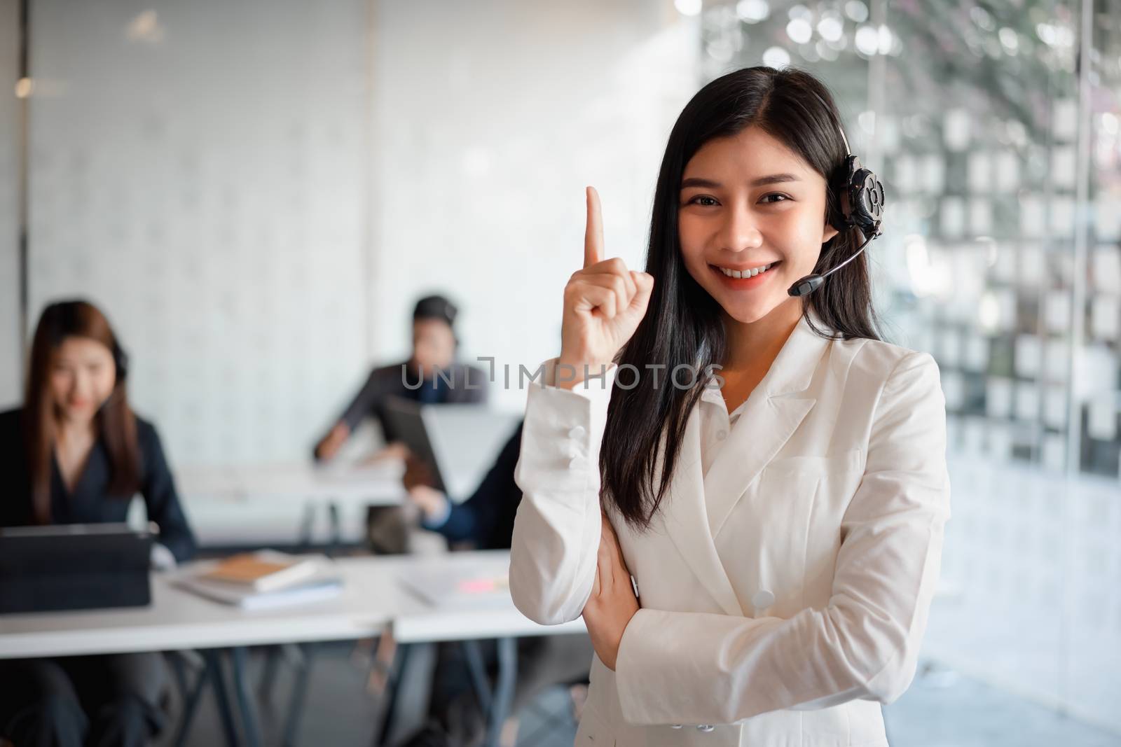 Confident female customer services agent with headset working in a call center office. Customer service team support concept by kenchiro75