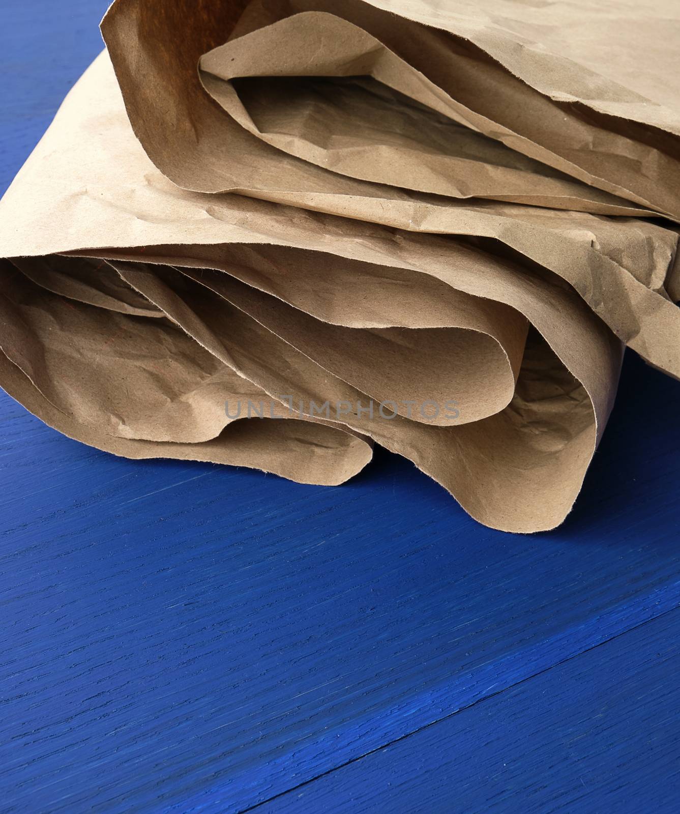 folded brown crumpled kraft paper sheet on blue wooden backgroun by ndanko
