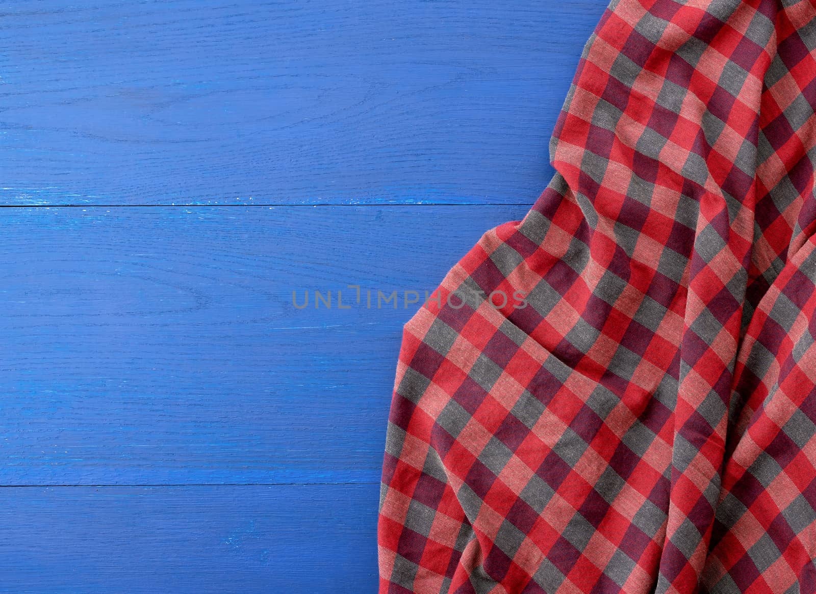 red checkered fabric on a blue wooden background, abstract background, place for an inscription