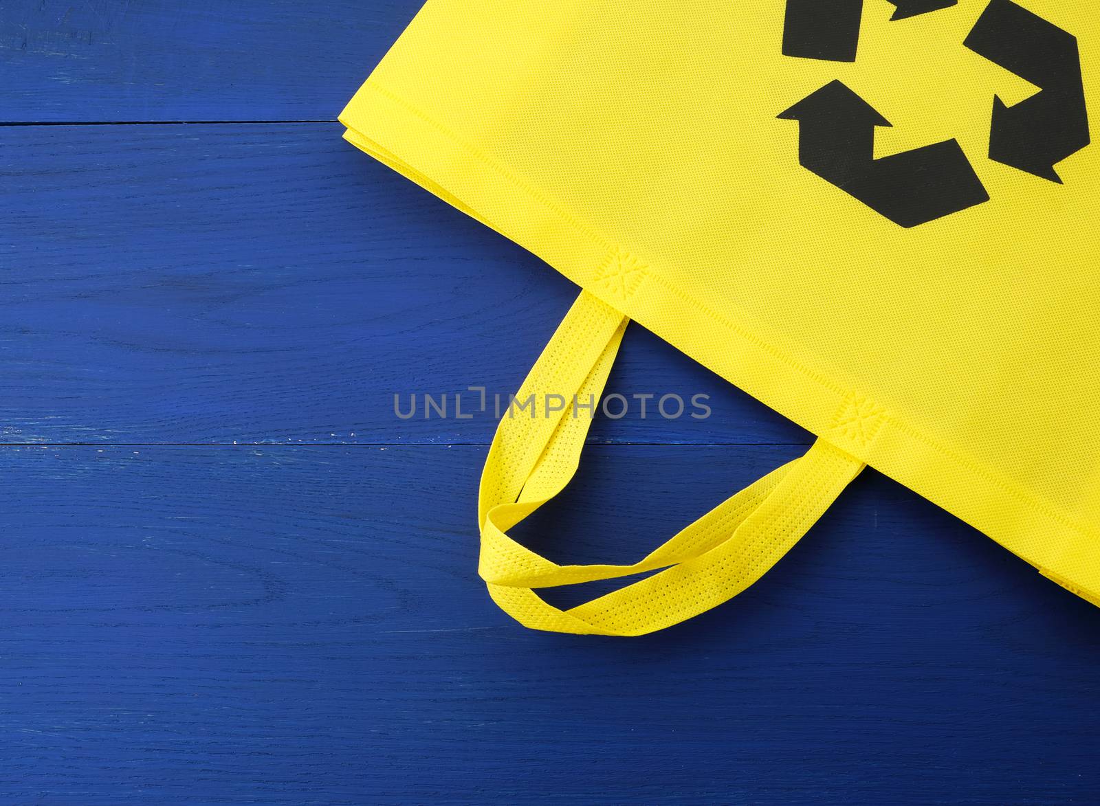 Reusable yellow viscose bag on blue wooden background, plastic waste reduction concept