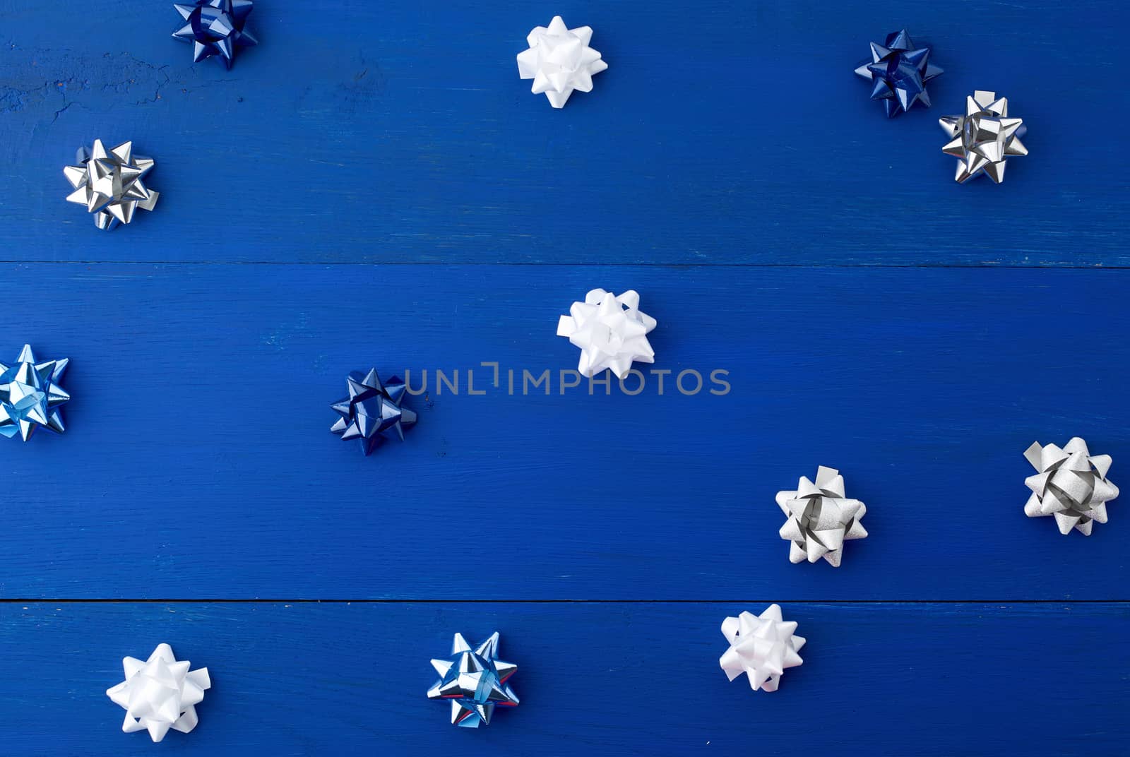 white, blue and gray bows for gifts on a blue wooden background, decor for decorating gifts, top view