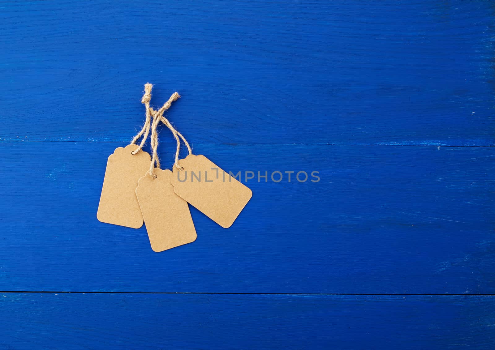 set of empty brown empty tags for clothes and other purposes on a blue wooden background. Paper craft