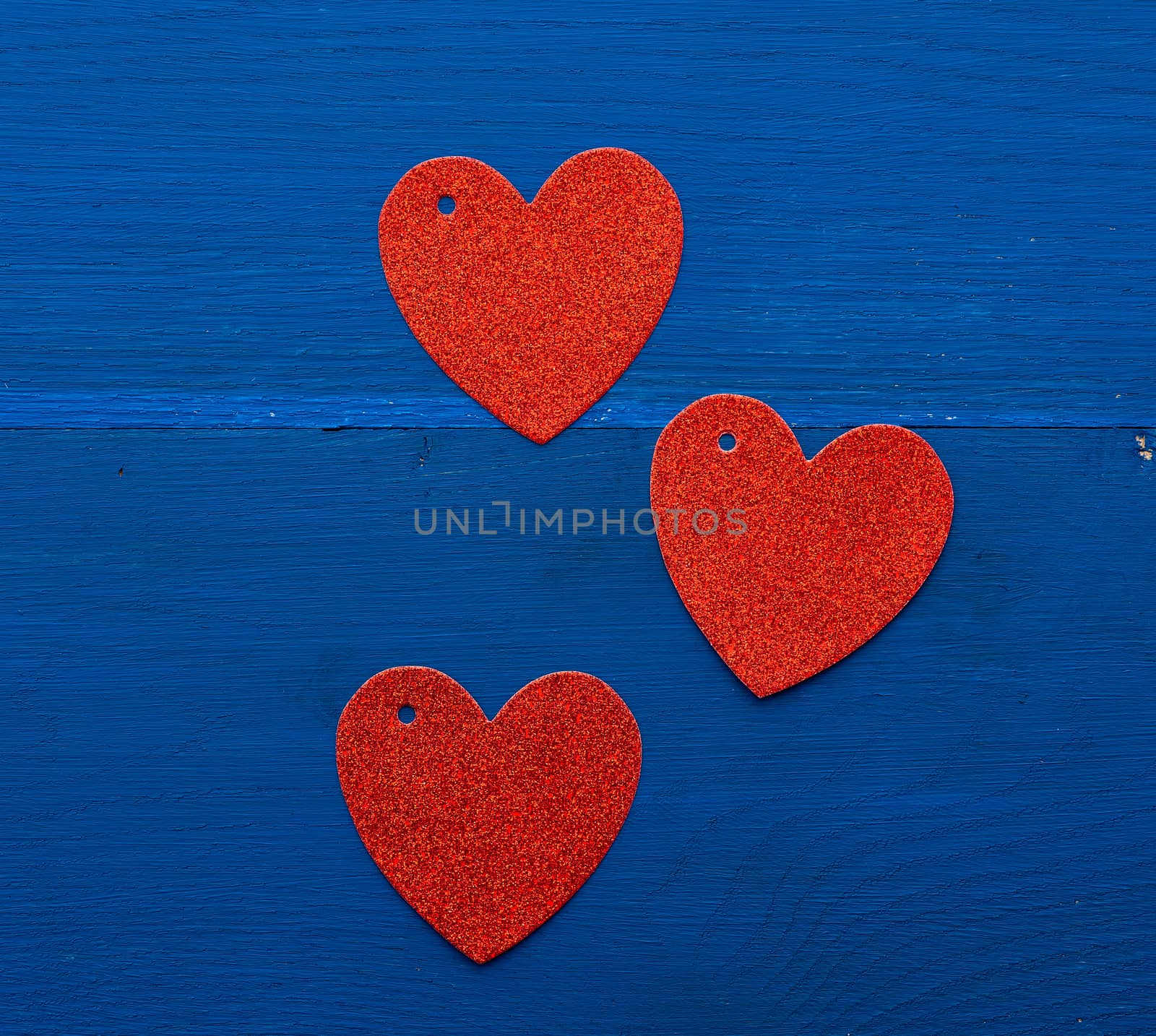 paper red shiny decorative hearts on dark blue wooden background, abstract festive backdrop for valentines day february 14