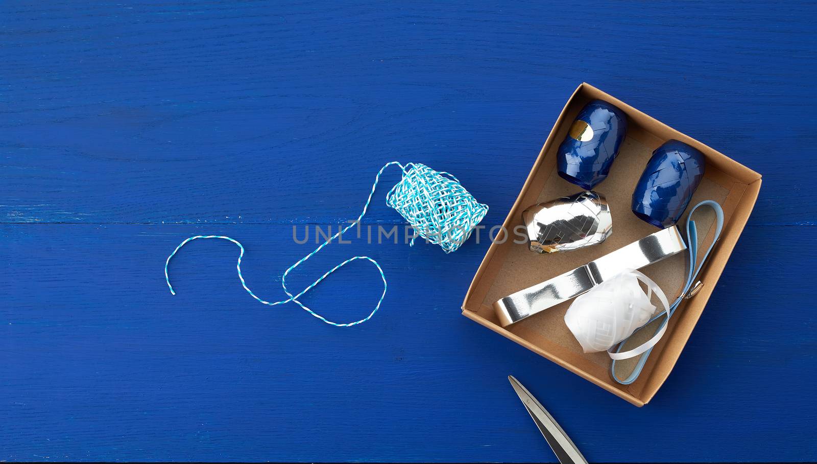 brown cardboard box with a set of decor ribbons for wrapping gifts on a dark blue background, top view