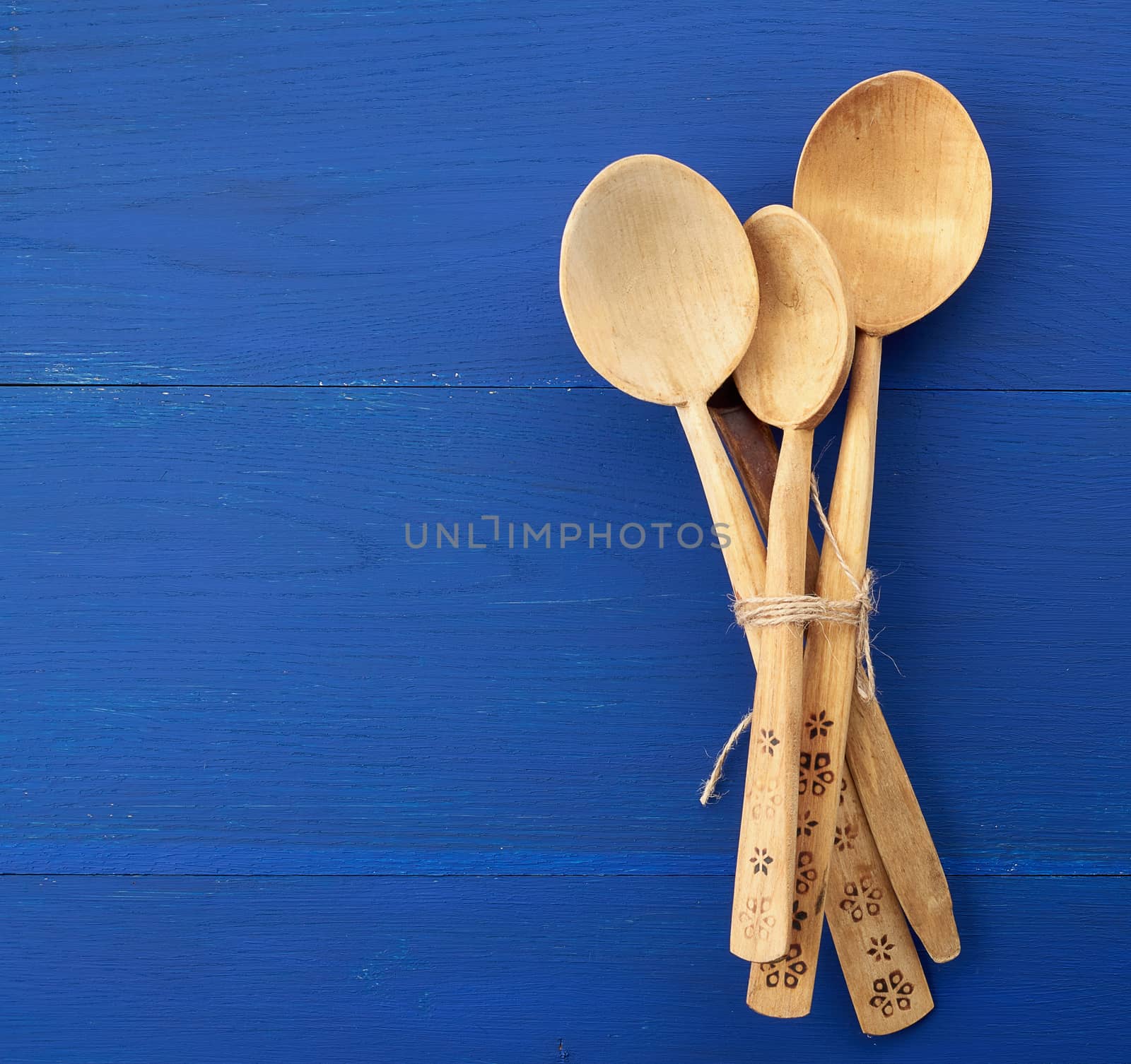 set of wooden vintage spoons tied with brown rope on a blue wooden background, top view