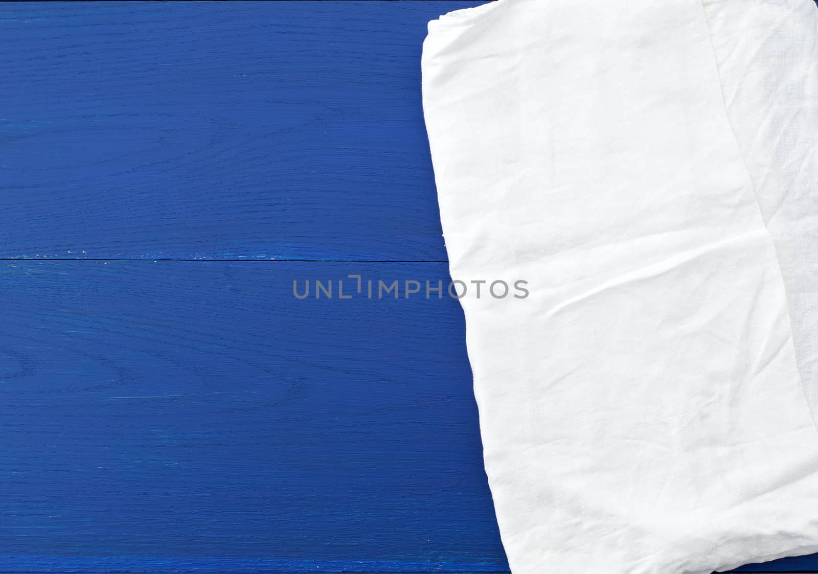 white kitchen textile towel folded on a blue wooden table from old boards, top view, empty space. Decoration element.