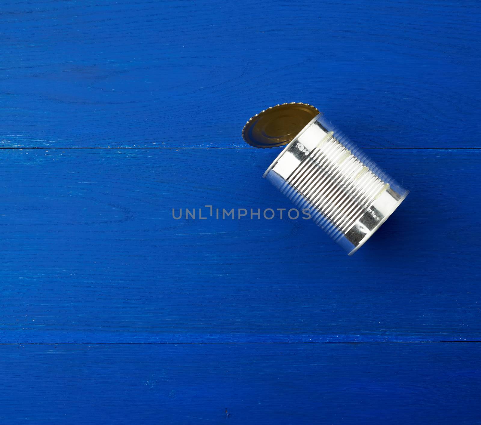 open large metal tin can on a blue wooden background from parallel boards, top view