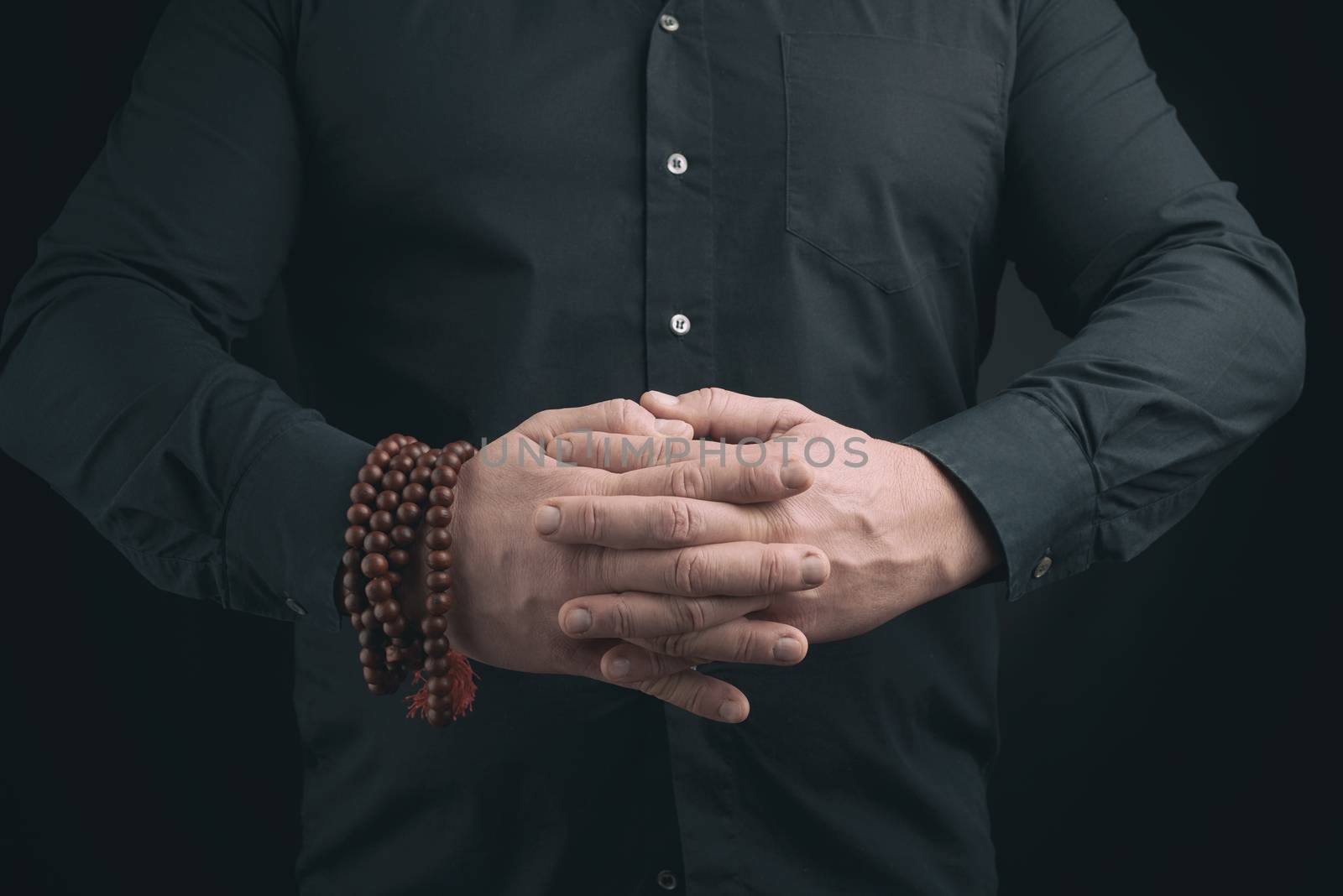 man in a black shirt crossed his arms in front of the torso, performing mudra, meditation