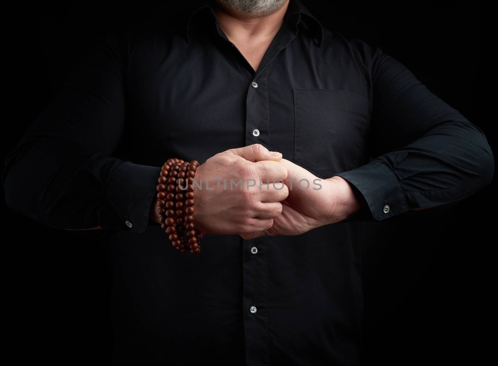 man in a black shirt crossed his arms in front of the torso, performing mudra, meditation