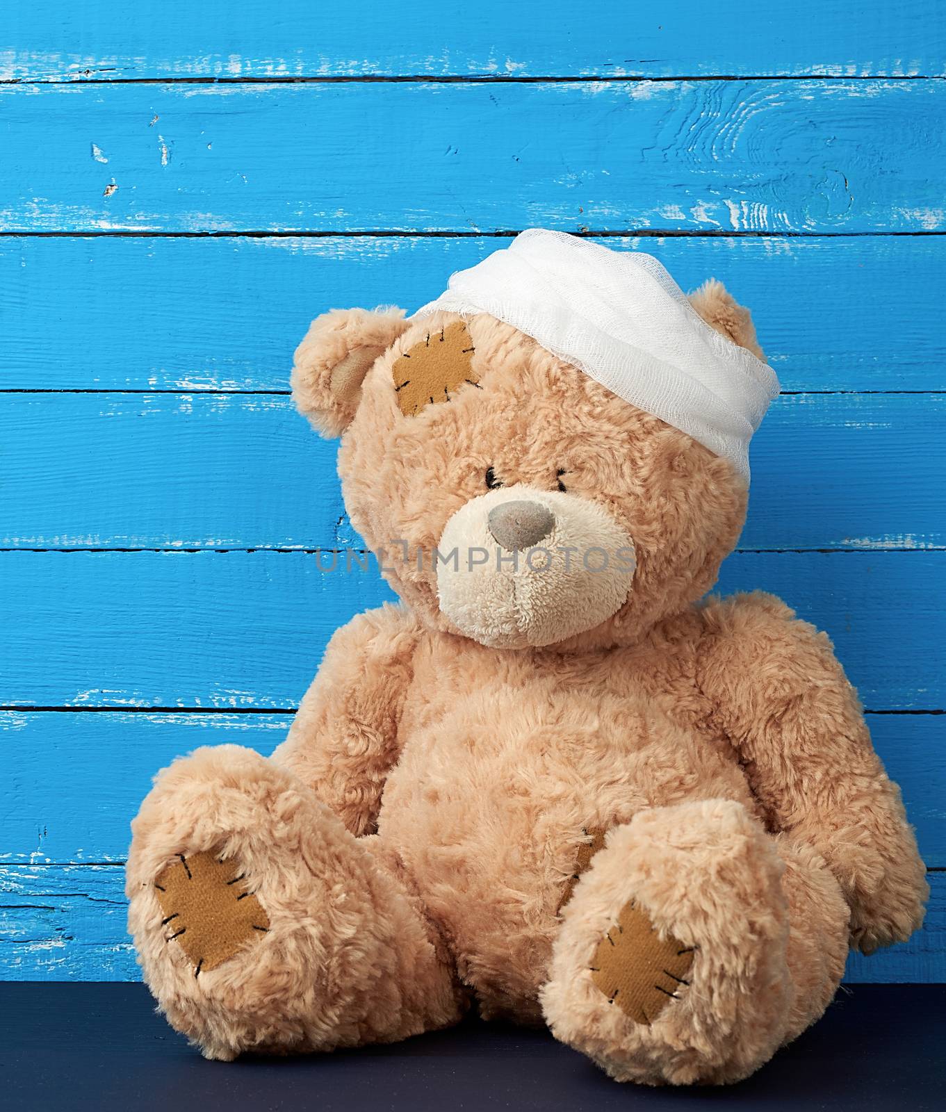 sad brown bear sits with bandaged white medical bandage head, injury and headache concept