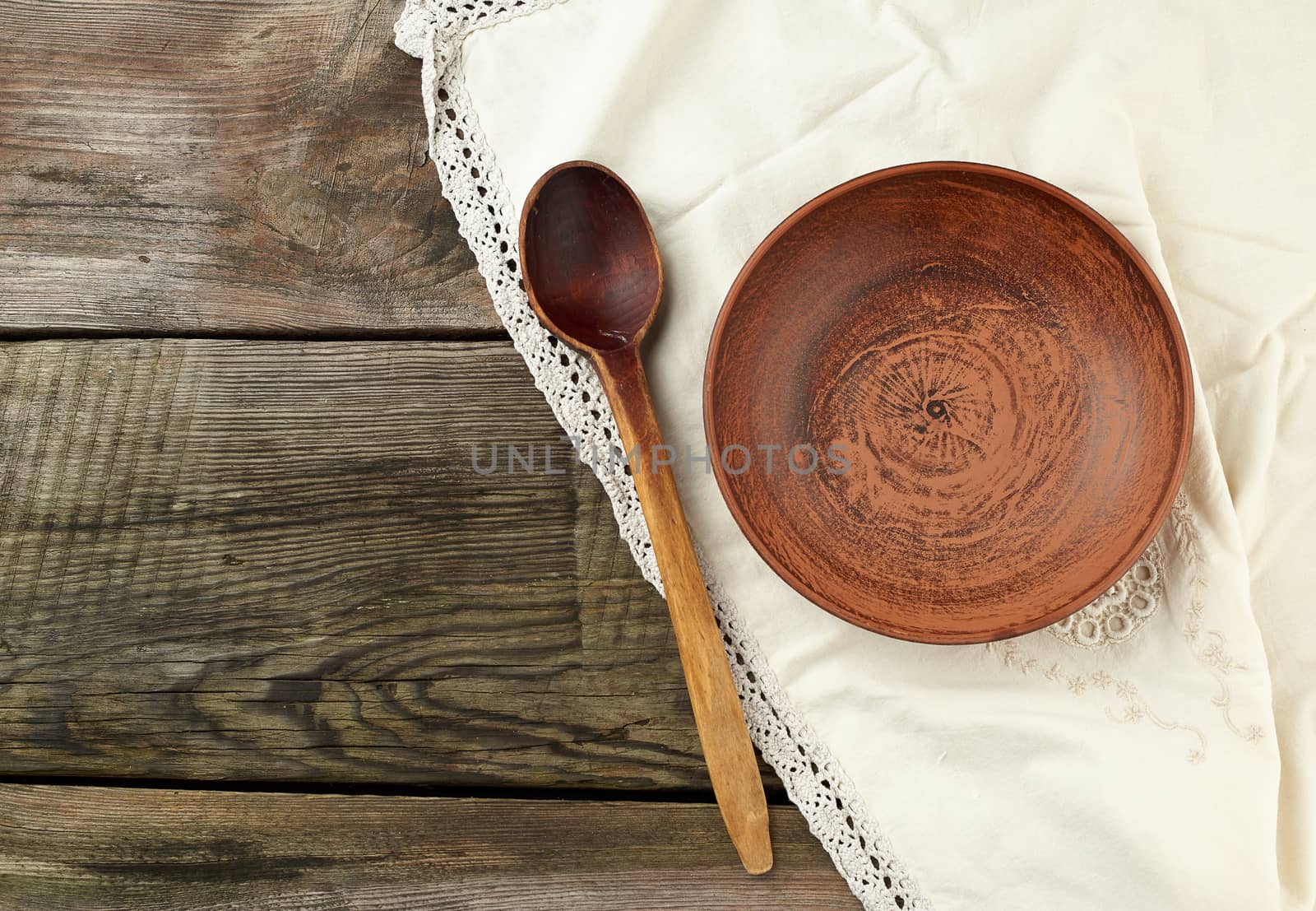 empty brown ceramic plates and wooden spoon on a wooden table, top view