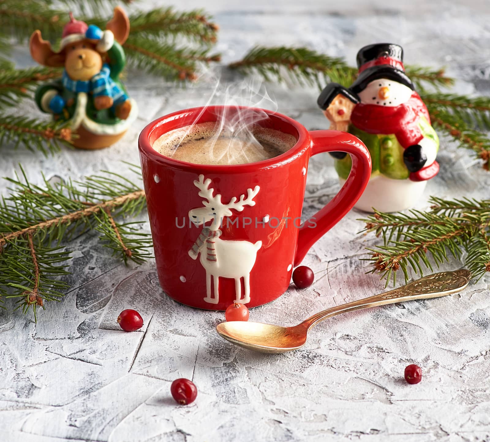 red ceramic cup with black coffee. near green branches of spruce and christmas toys