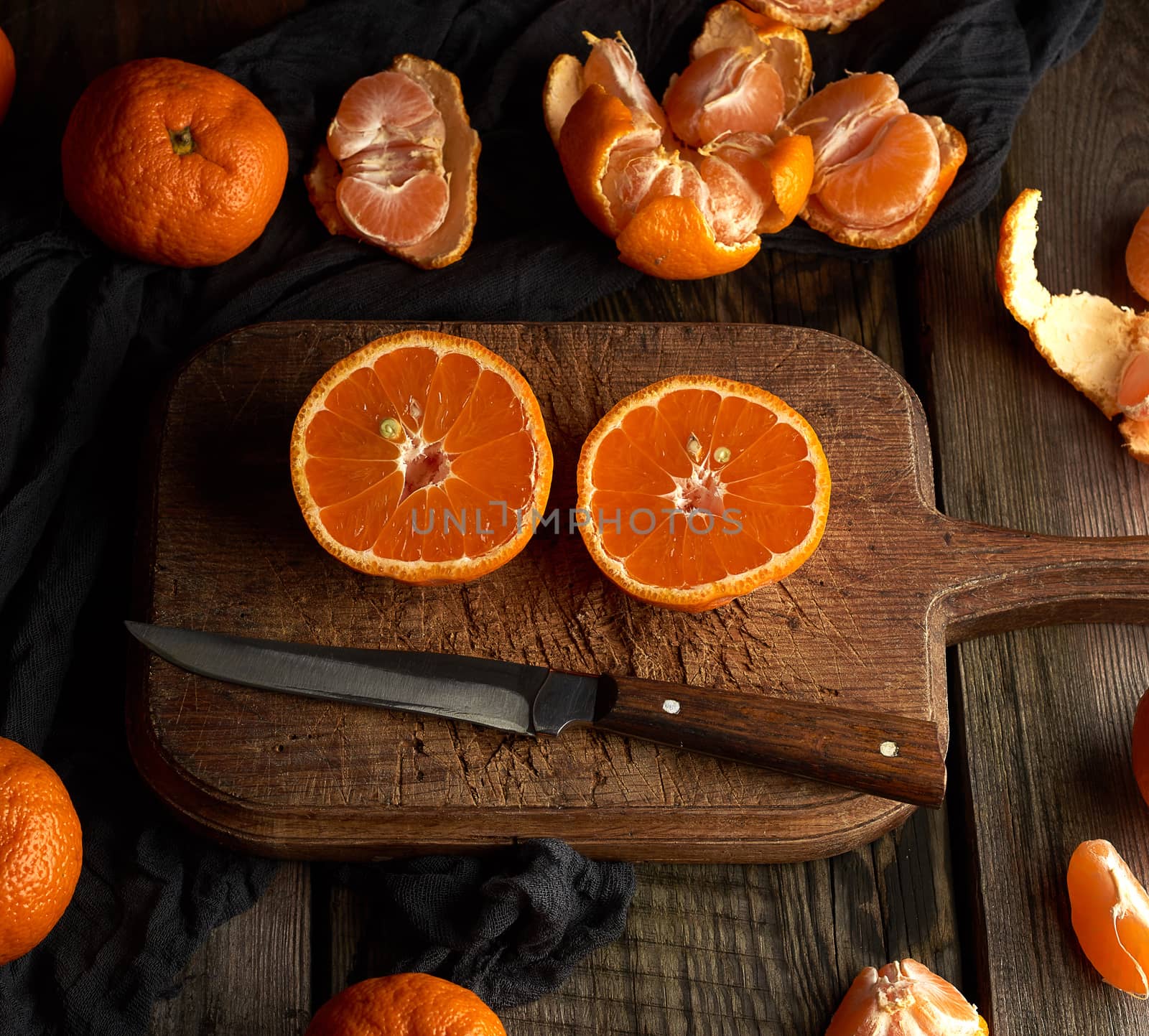 ripe round tangerines and cut in half on an old vintage cutting board. Healthy vegetarian food. Citrus fruit.