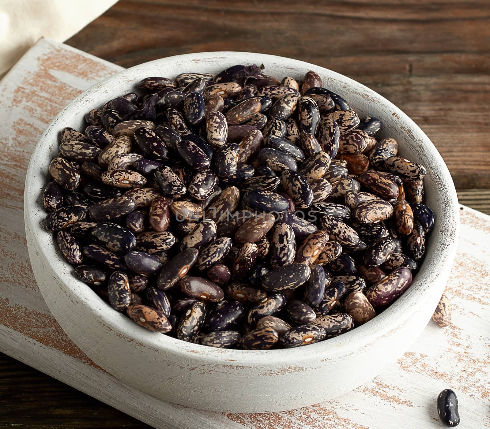 raw oval red marble beans in a plate on a wooden table. Agriculture harvest. Vegetarian healthy natural food.