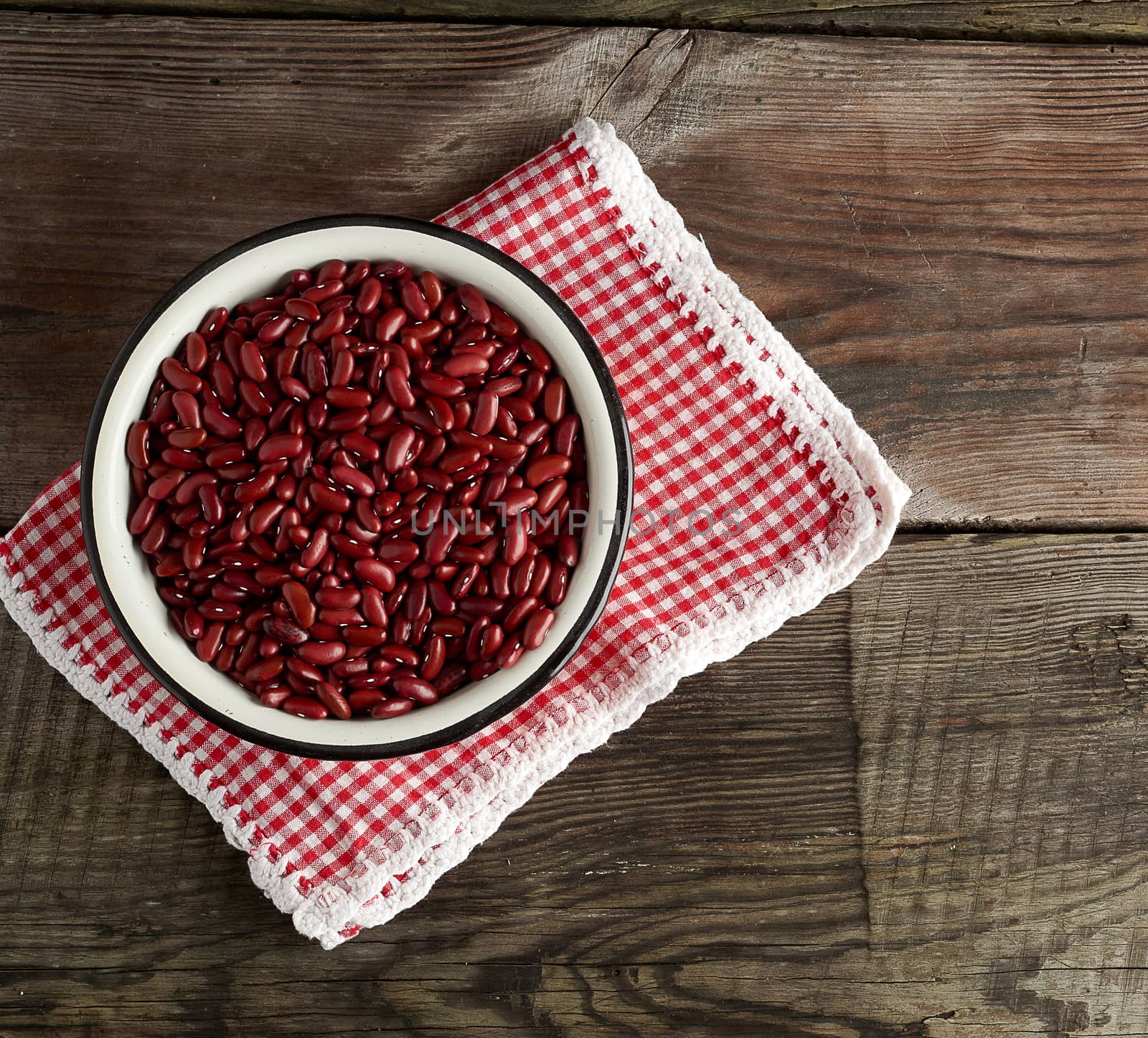 raw oval red beans in a plate on a wooden table. Organic meal. Vegetarian healthy natural food.