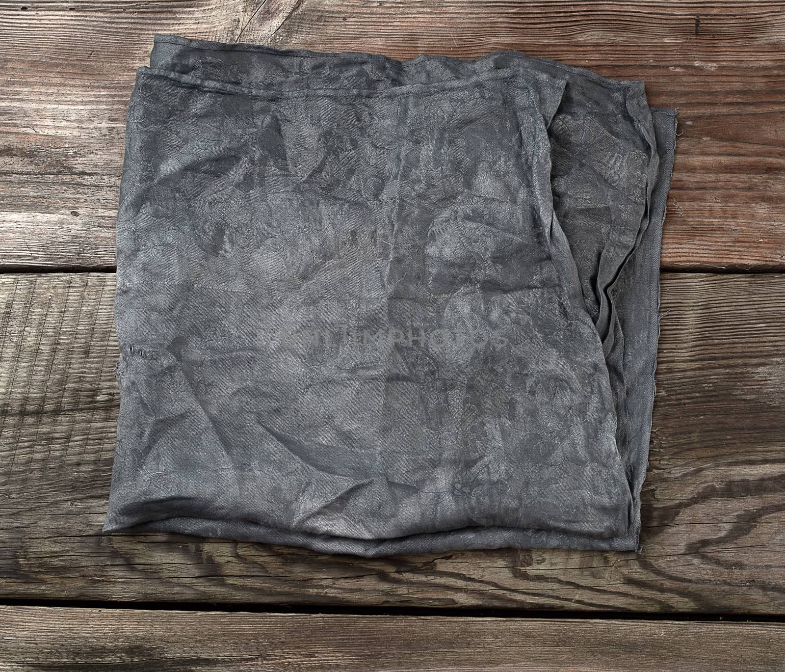black textile kitchen towel on a wooden background from old gray boards, place for an inscription, top view