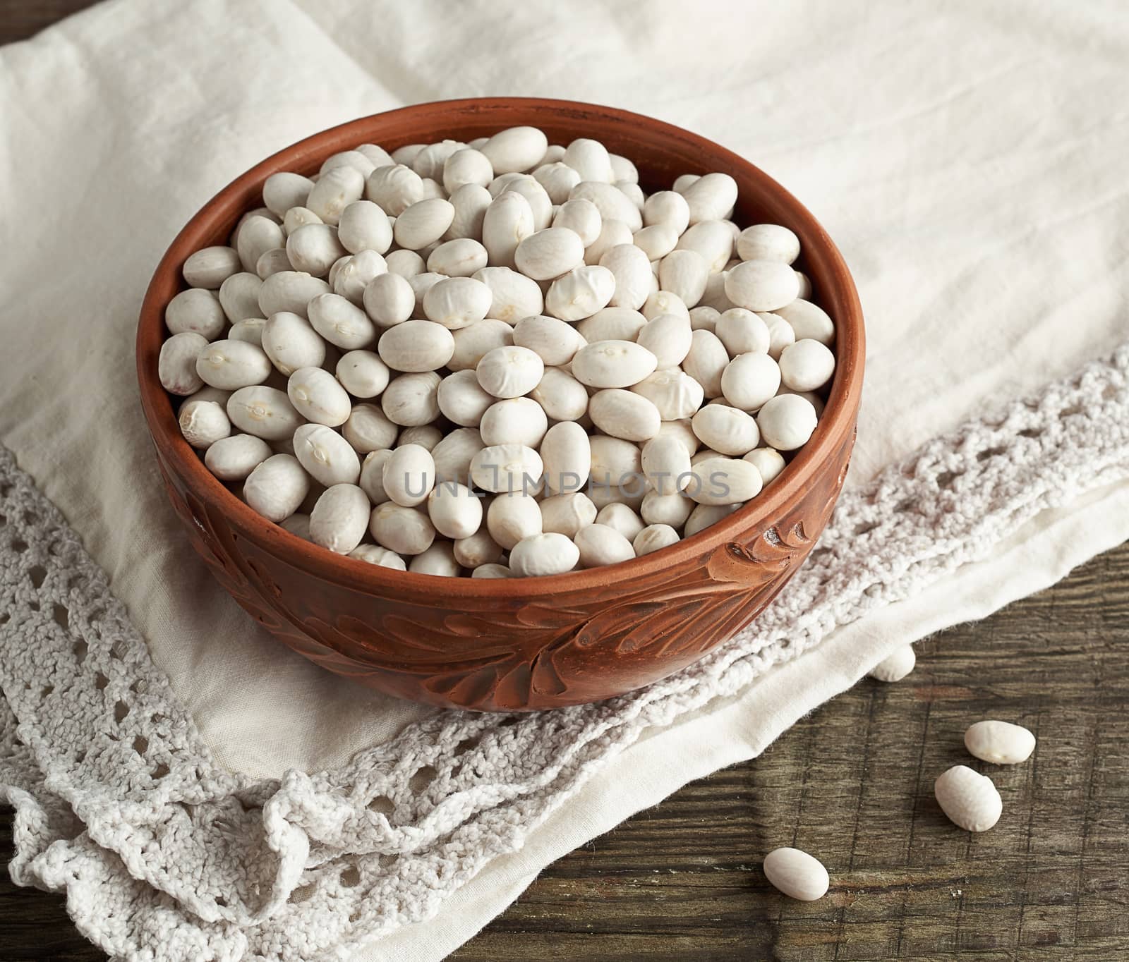 raw round white beans in a plate on a wooden table. Organic meal. Vegetarian healthy natural food.