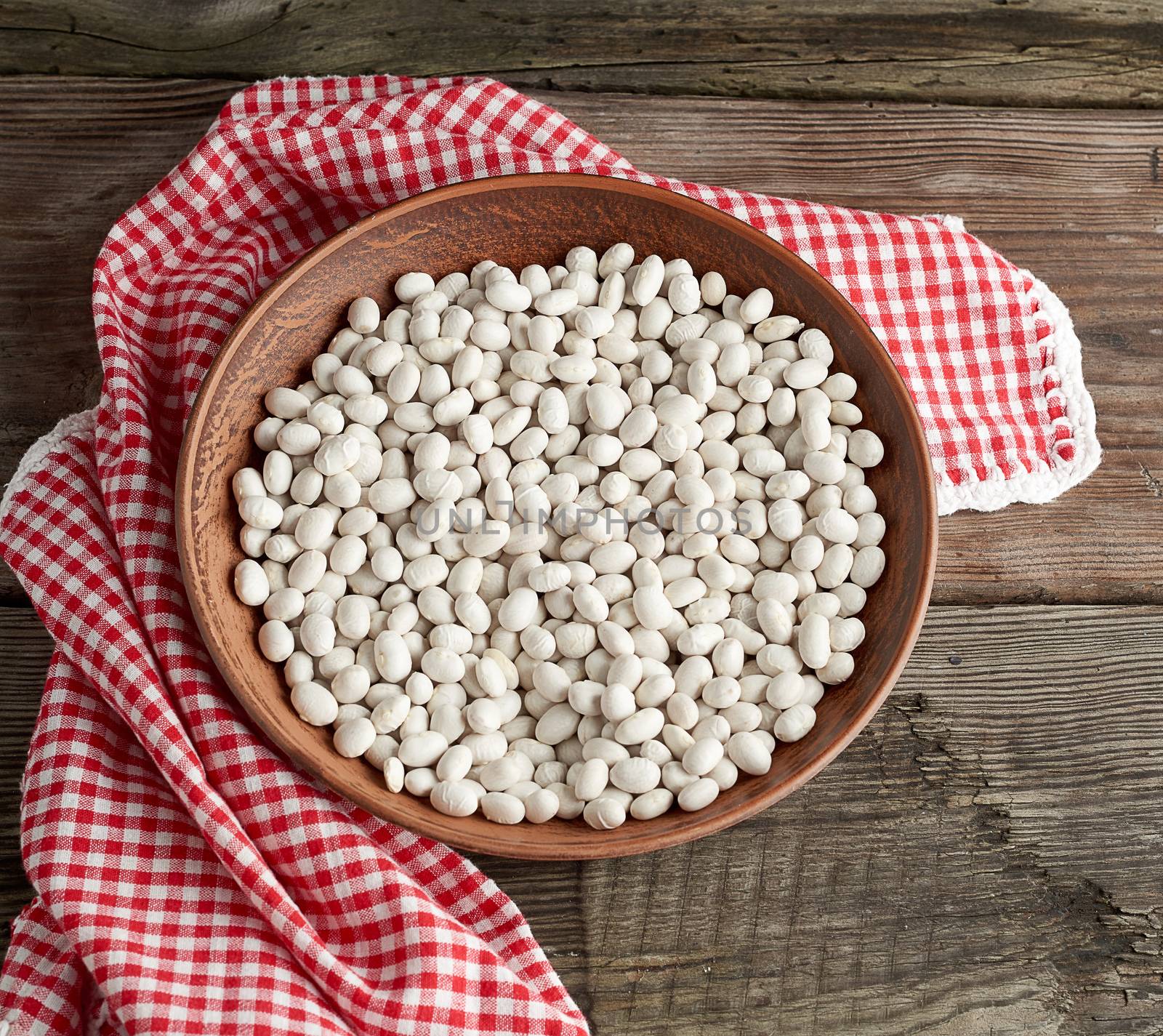 raw round white beans in a plate on a wooden table. Organic meal. Vegetarian healthy natural food.