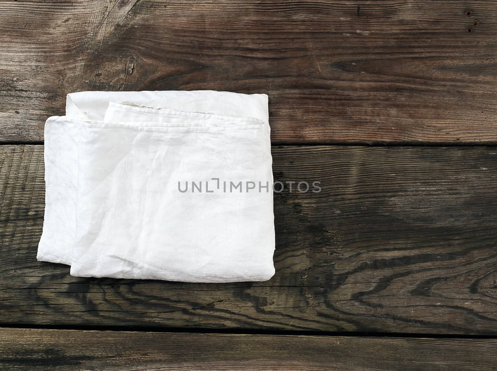 white kitchen textile towel folded on a gray wooden table from old boards, top view, empty space. Rustic texture. Retro background