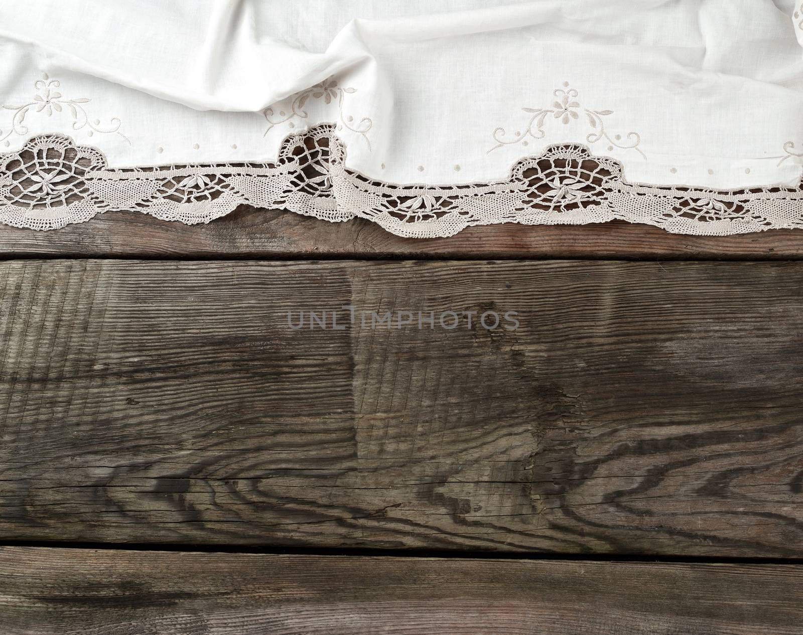 white kitchen textile lace towel folded on a gray wooden table from old boards, top view, empty space