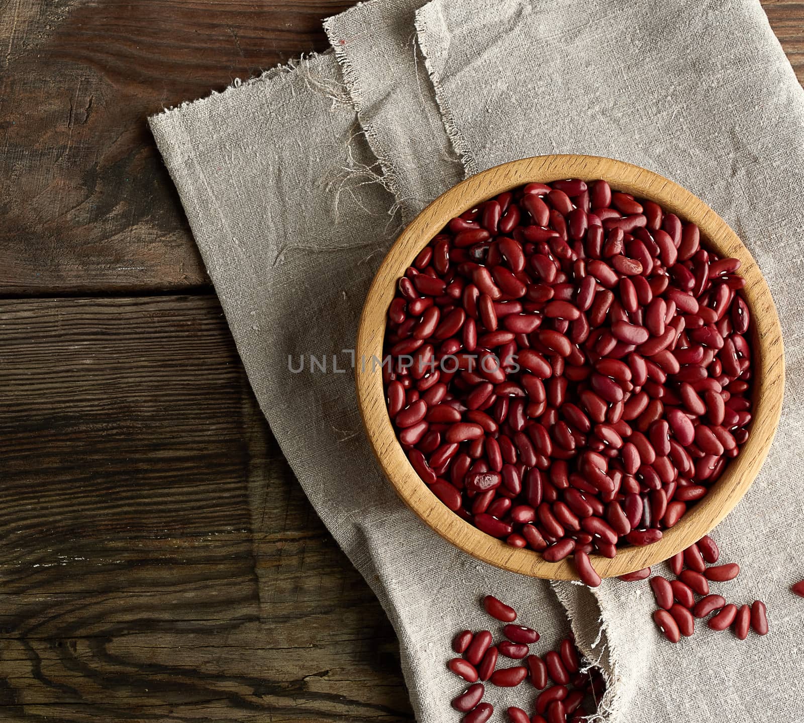 raw oval red beans in a plate on a wooden table. Organic meal. Vegetarian healthy natural food.
