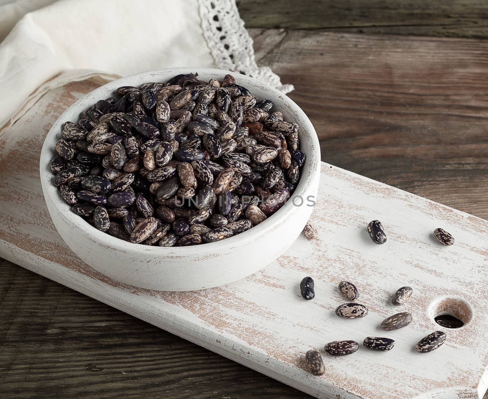 raw oval red marble beans in a plate on a wooden table. Agriculture harvest. Vegetarian healthy natural food.