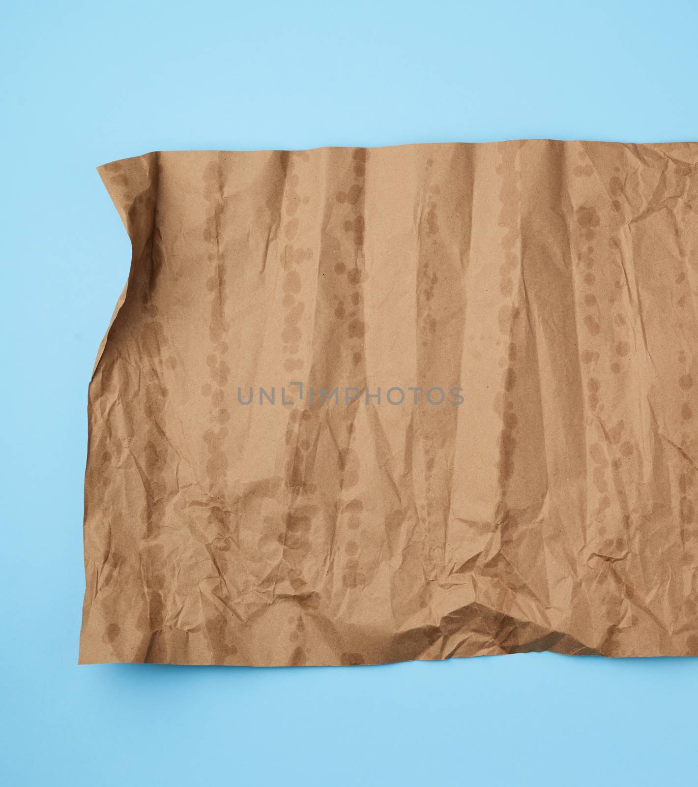 crumpled brown sheet of paper for packaging goods on blue background