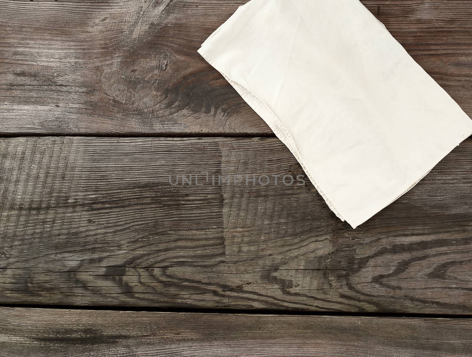 white kitchen textile towel folded on a gray wooden table from old boards, top view, empty space. Rustic texture. Retro background