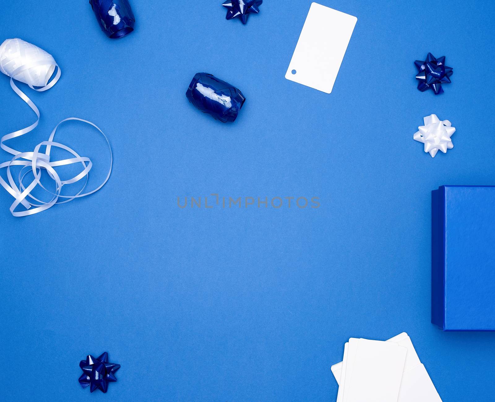 cardboard gift square boxes, bows, ribbons for packaging on a dark blue background, empty space in the middle, trend colors