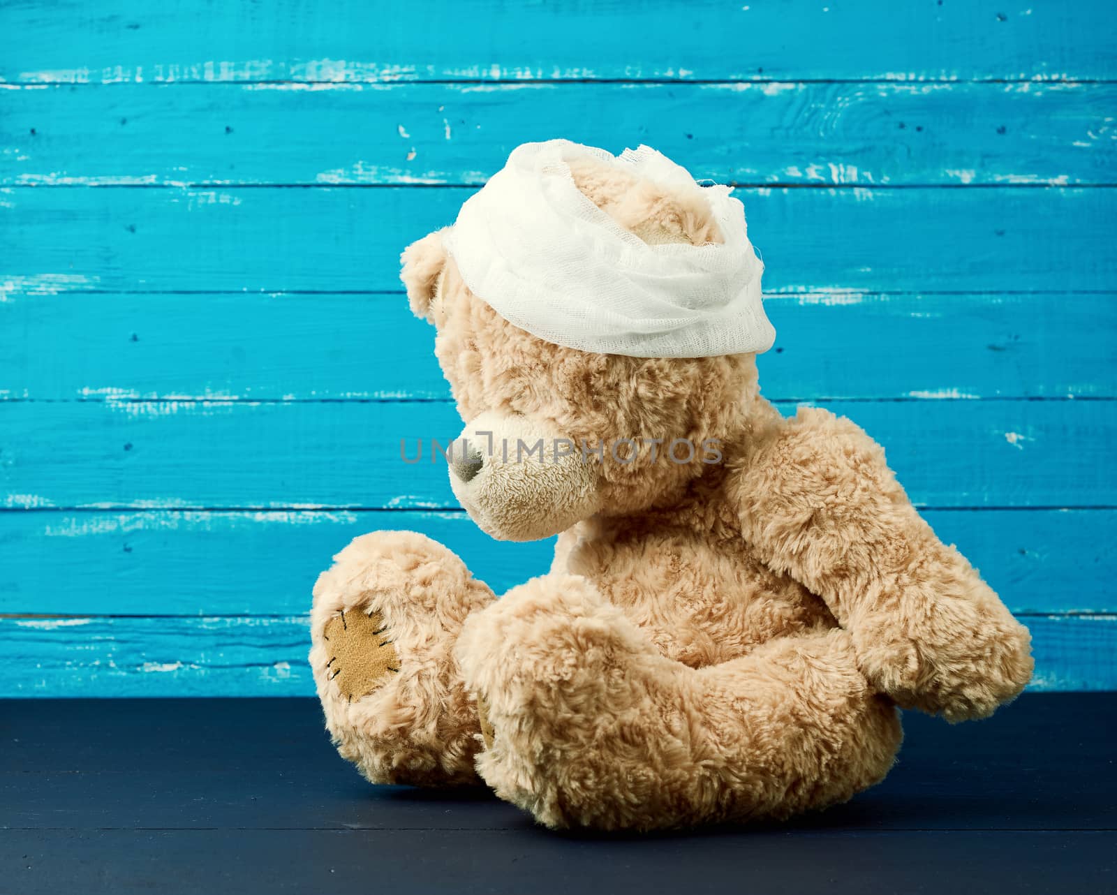 sad brown bear sits with bandaged white medical bandage head,injury and headache concept