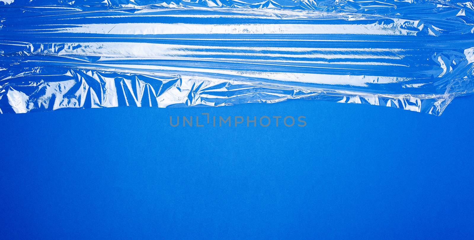 texture of a transparent stretching plastic film for packaging products on a blue background, full frame,copy space