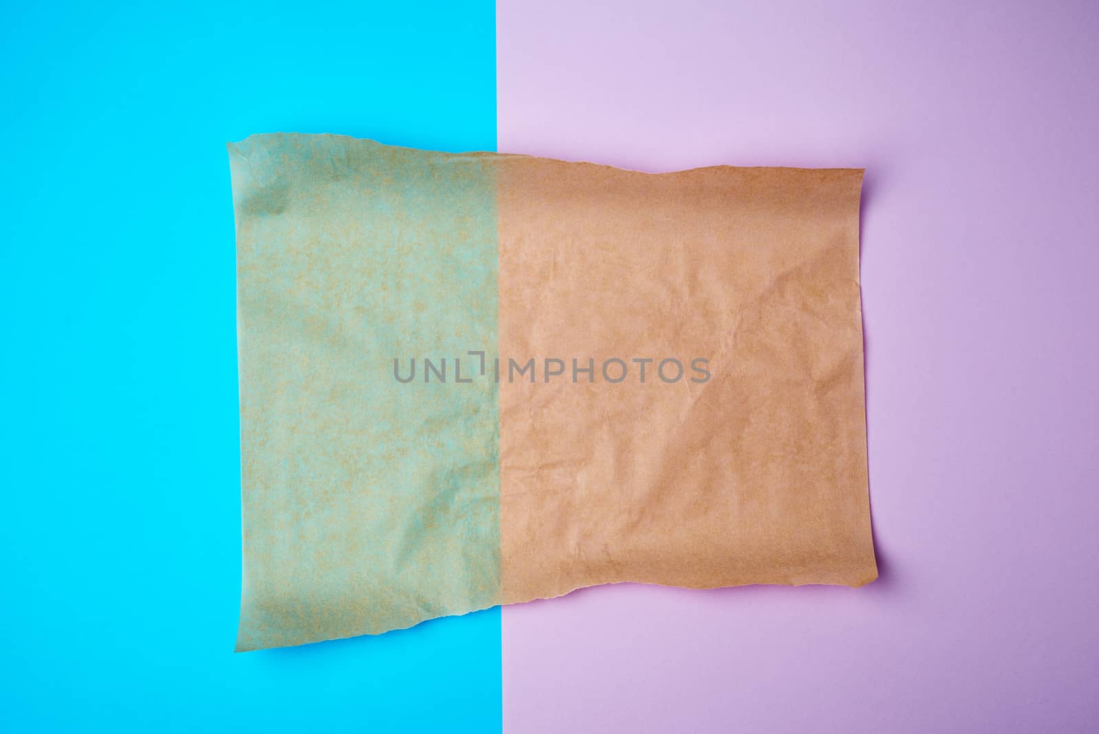 empty brown sheet of parchment paper with curled edges on a colored background, copy space