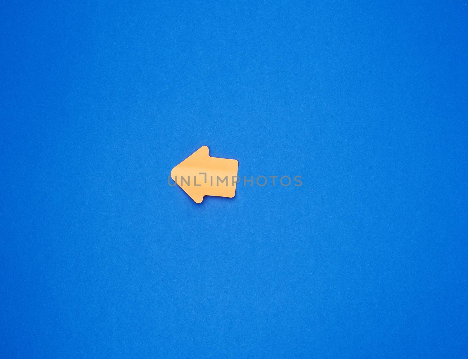 orange paper sticker in the form of an arrow pointer is glued on a blue background, place for an inscription