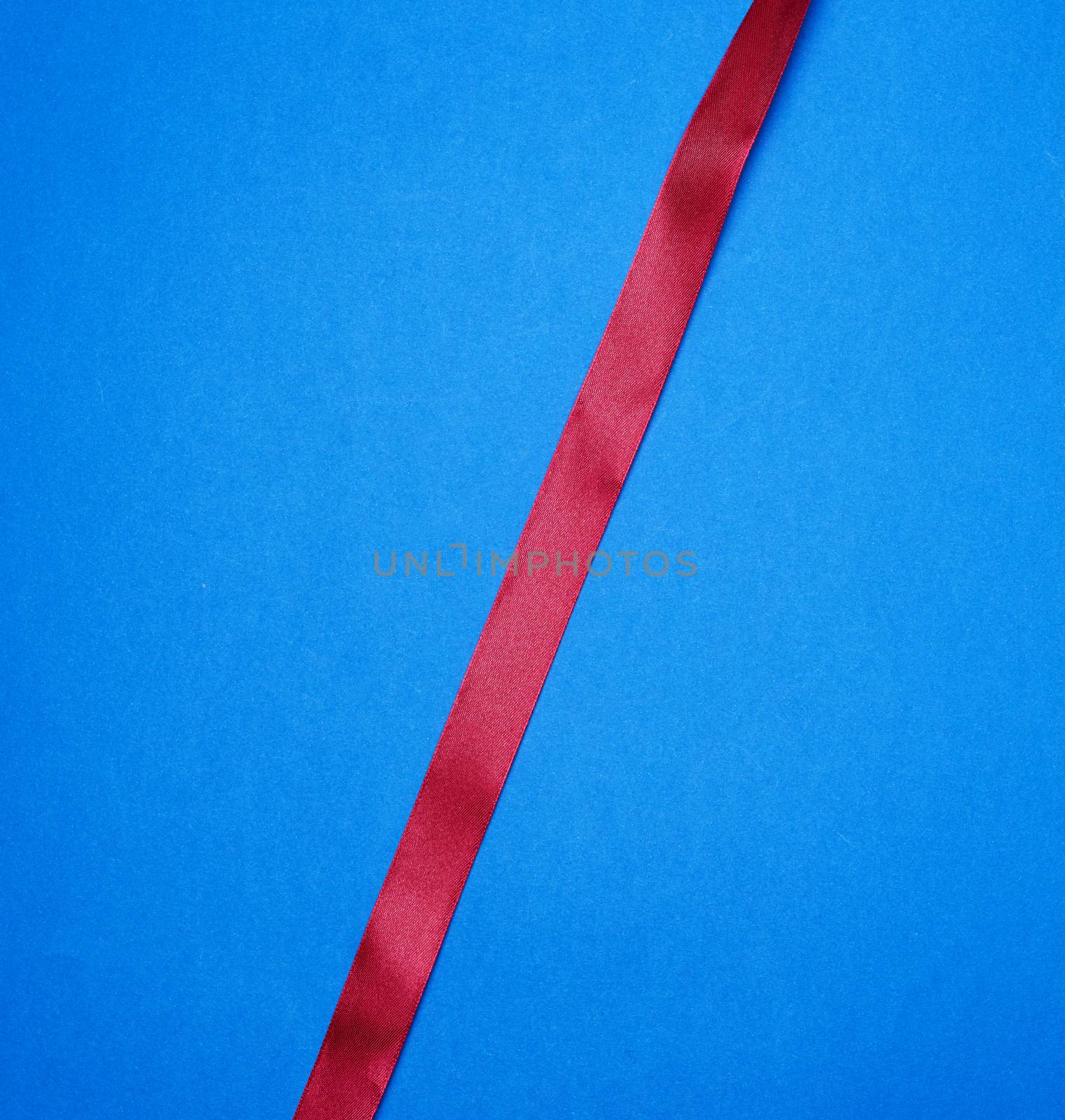 red silk thin ribbon on a blue background, close up