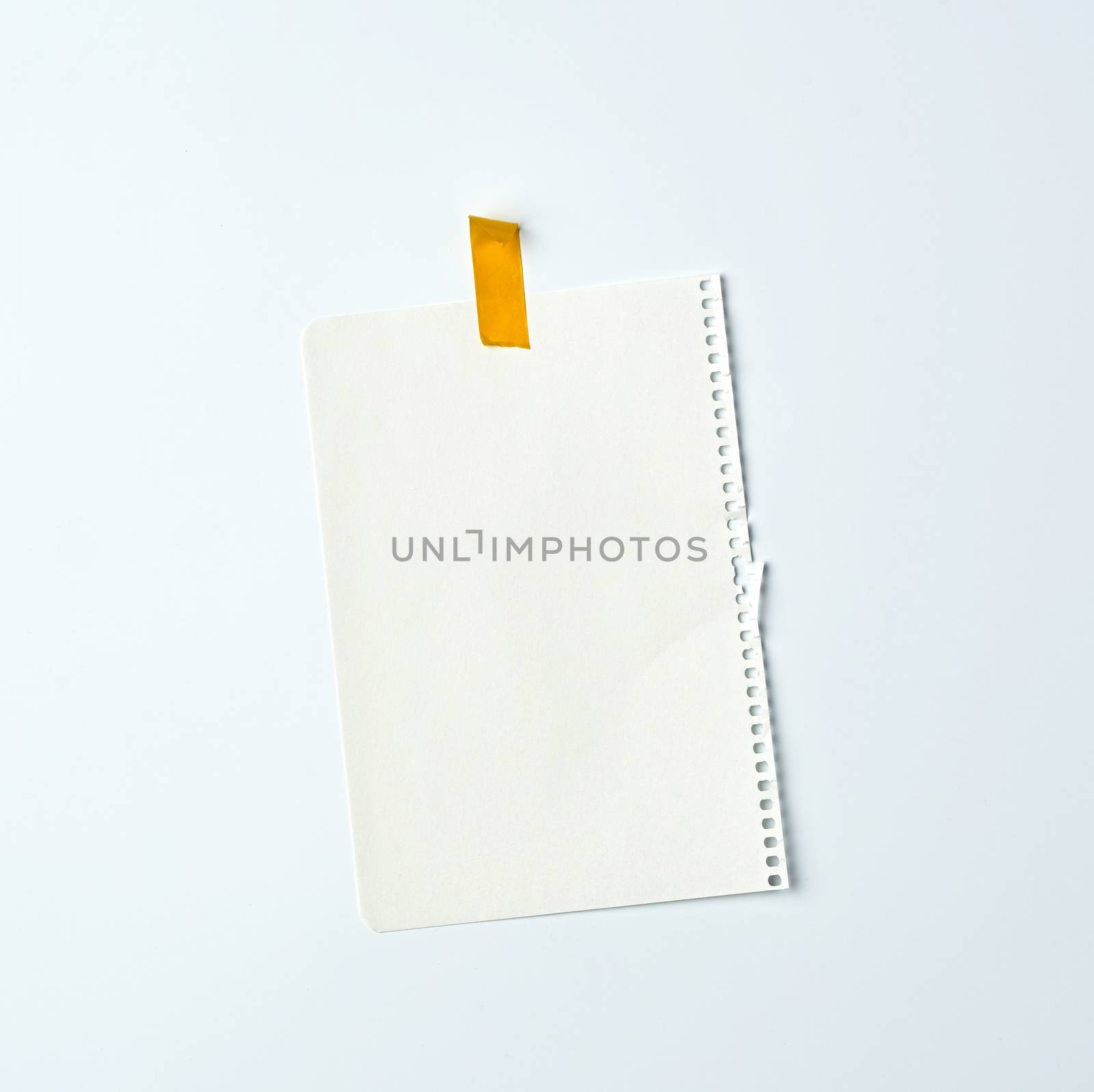 white crumpled sheet of paper torn from a spiral notebook and glued with yellow electrical tape on a white background, place for text. Design space
