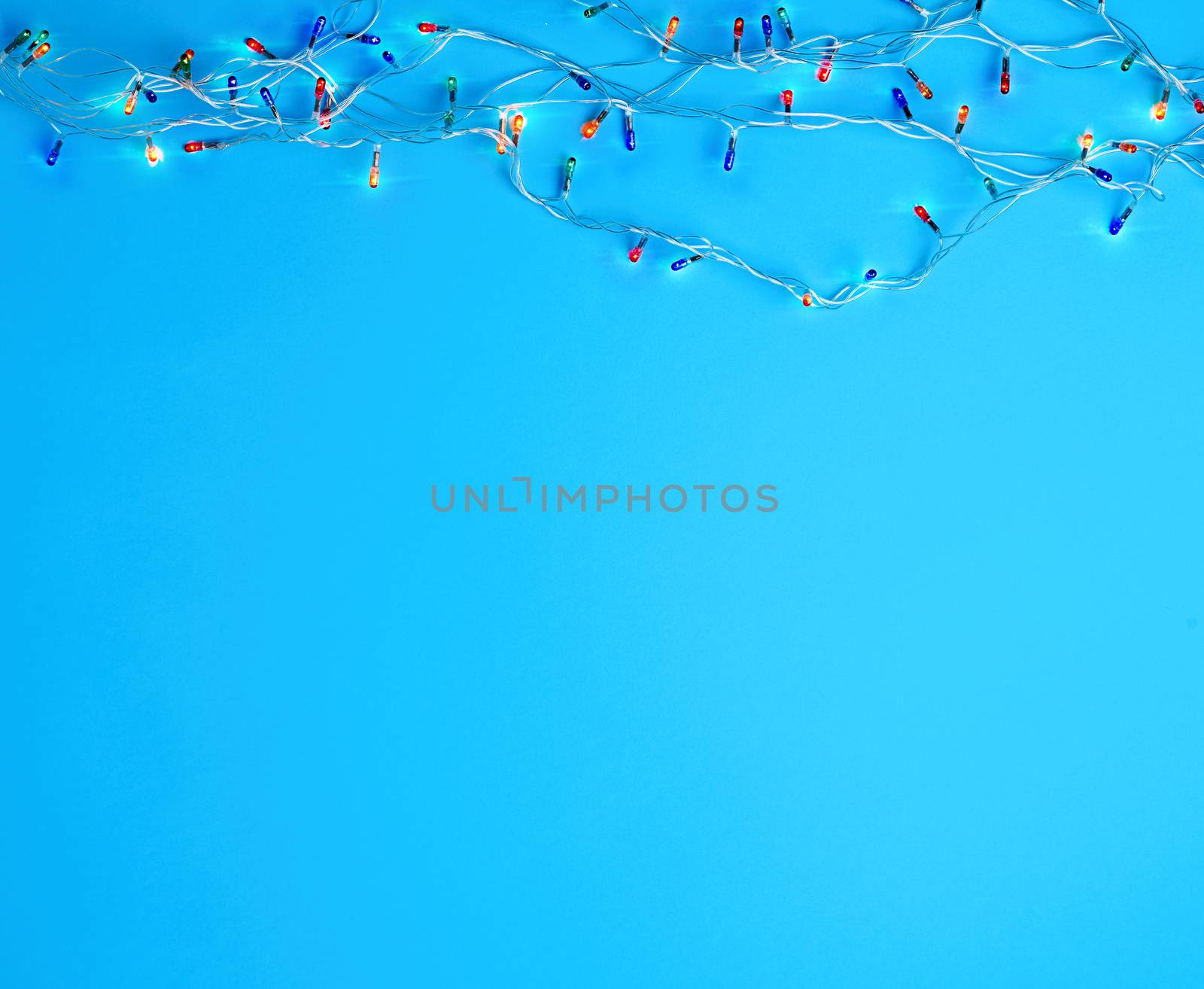 burning christmas garland on a white wire with colorful lights on a blue background, coy space