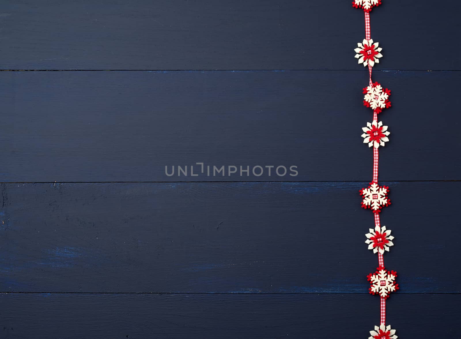 white red felt snowflakes on a blue wooden surface, empty space