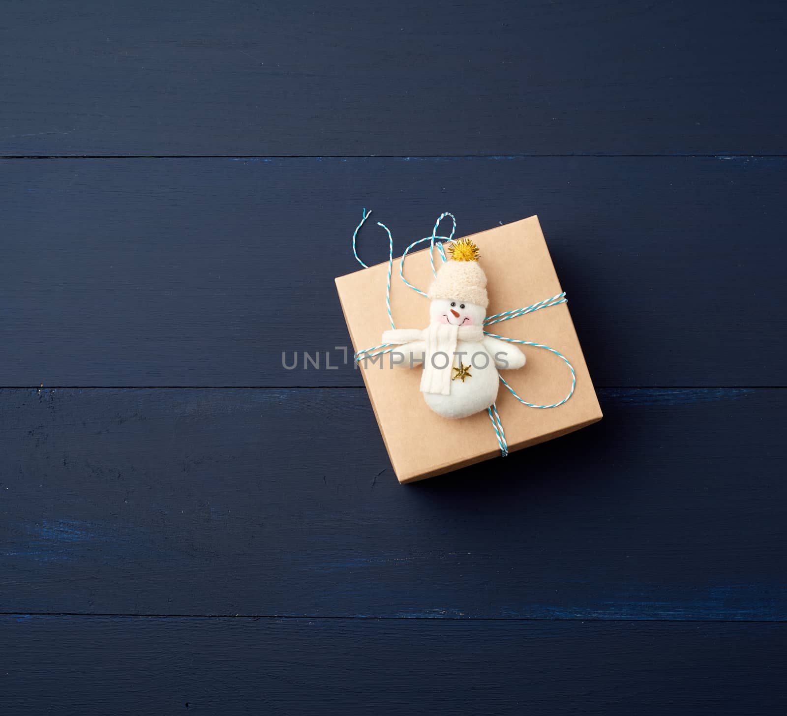 brown cardboard gift square box on a blue wooden background, top view. Festive concept, copy space