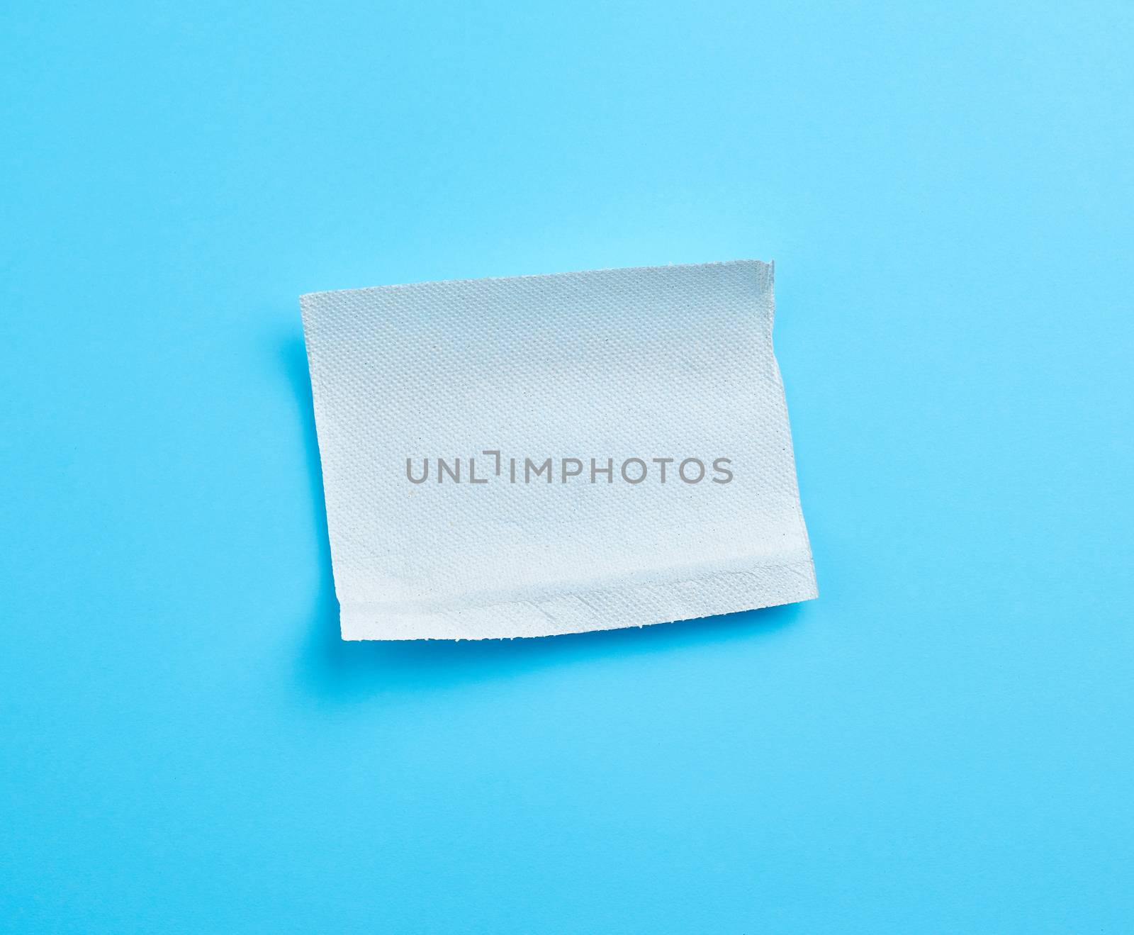 torn soft white sheet of paper towel with curled corners on a blue background