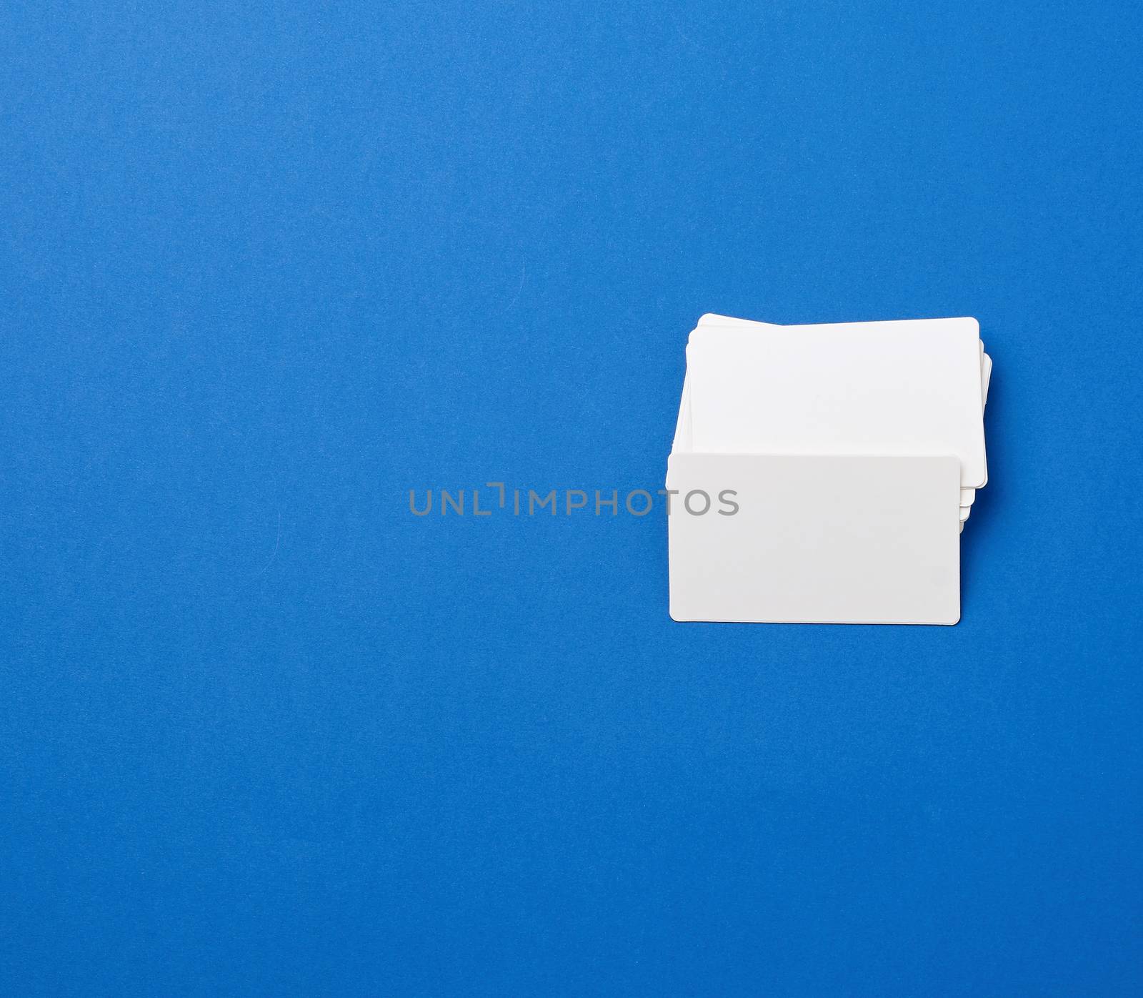 stack of rectangular white blank business cards on a blue background. Corporate business concept